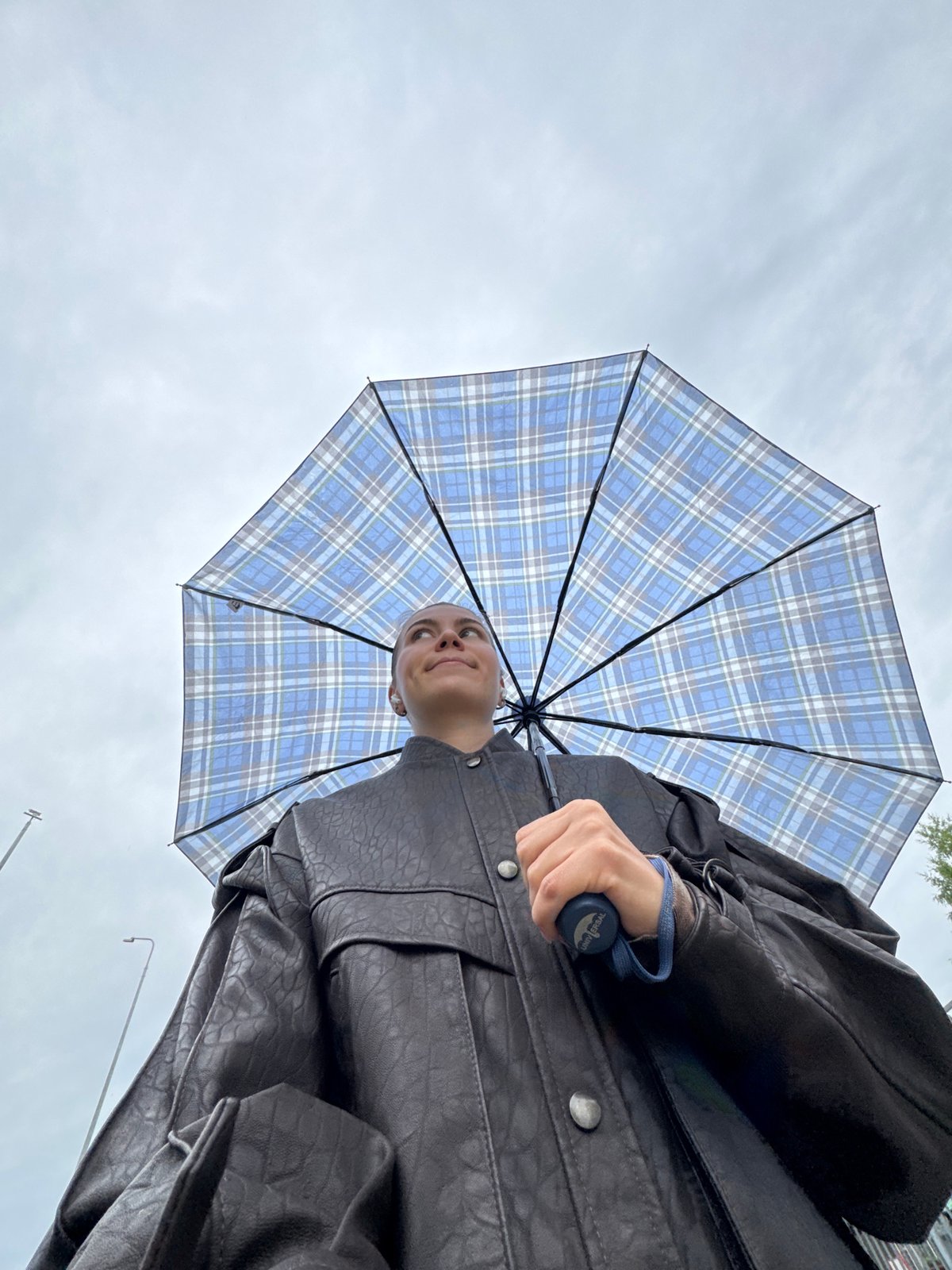 Outfit check: leather jacket, plaid layers, umbrella in hand