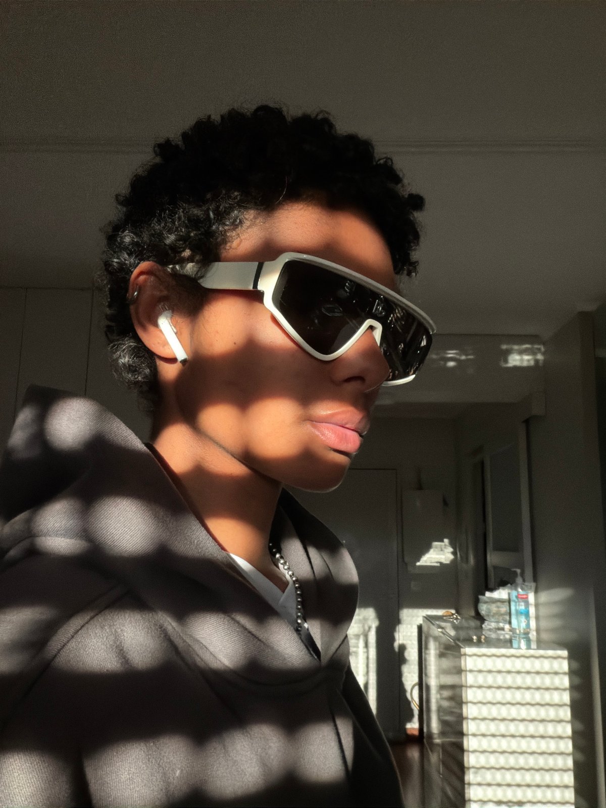 Person in gray hoodie, white sunglasses observed indoors Champs-sur-Marne