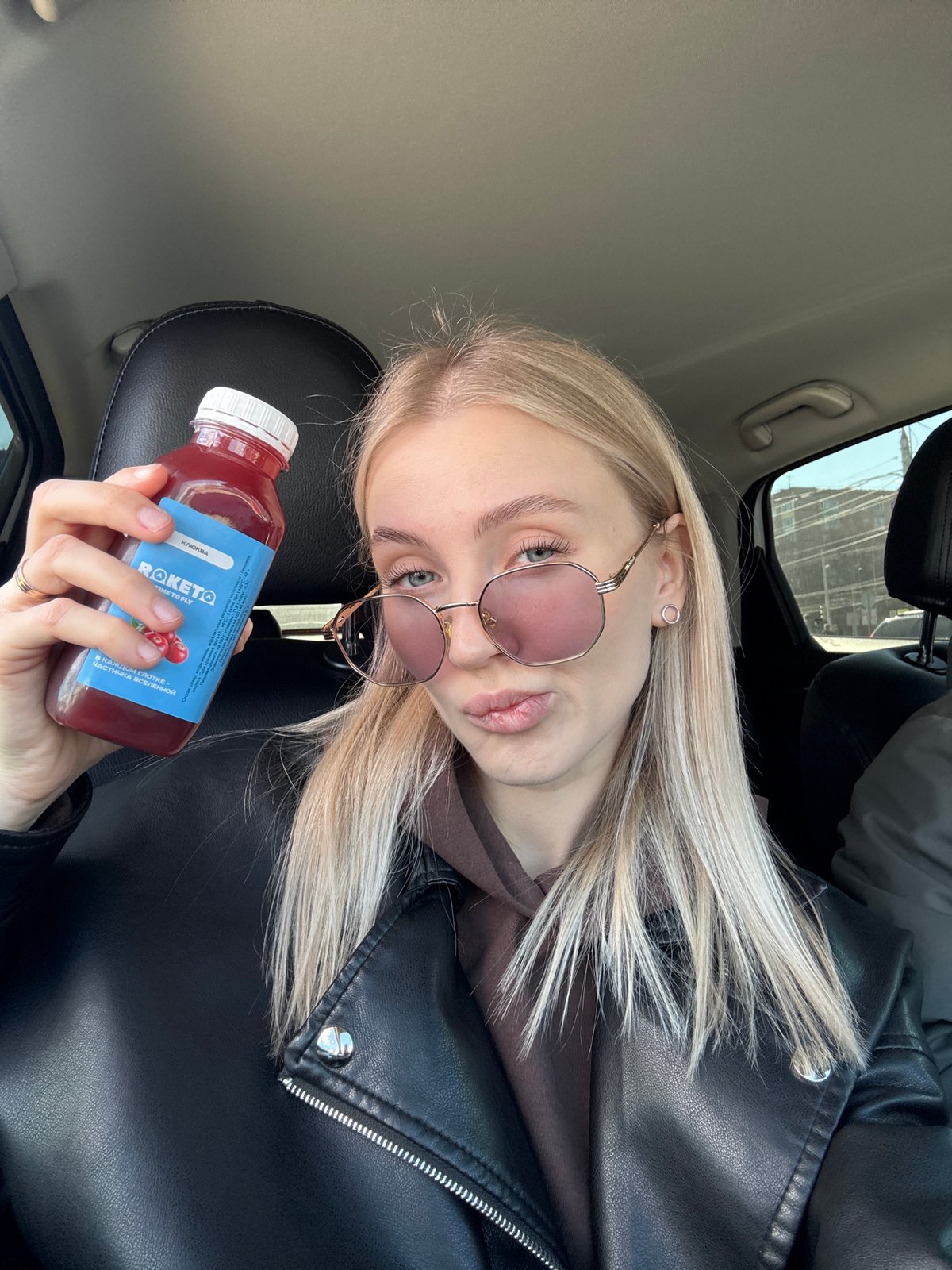 Woman enjoys cranberry juice in convertible car in Izhevsk
