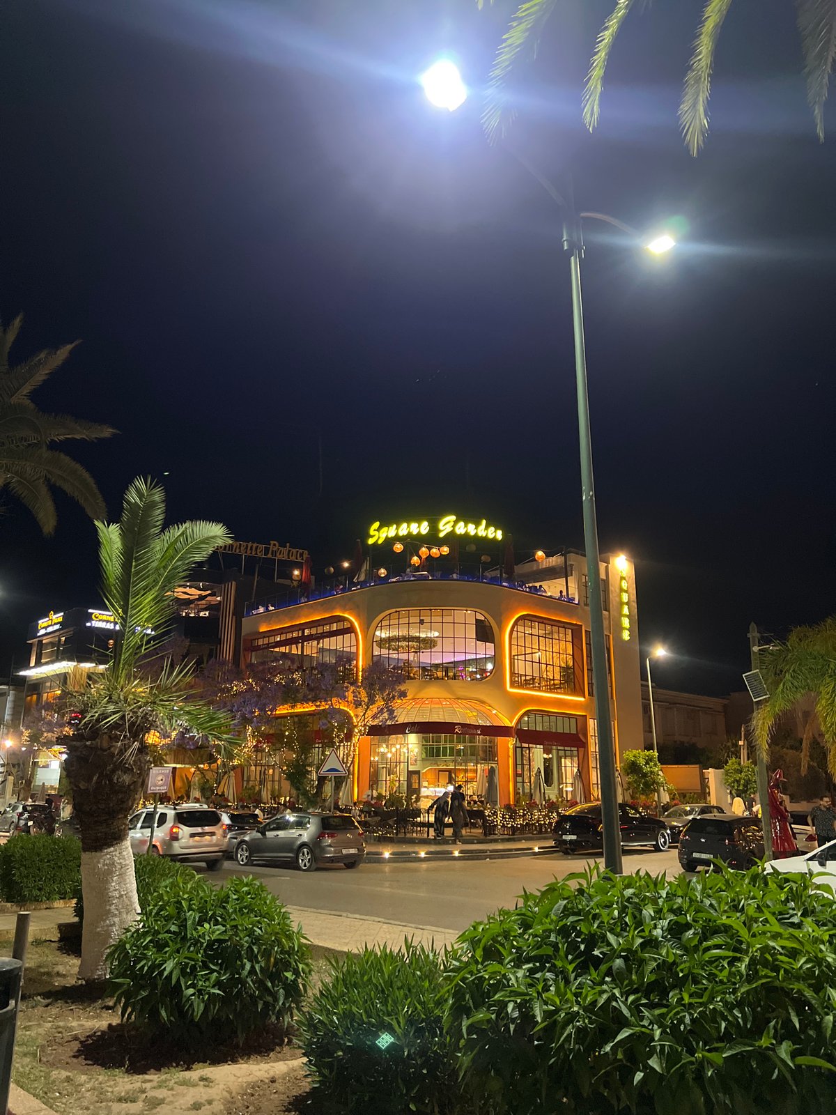 Evening gathering at illuminated Square Garden building in Meknes
