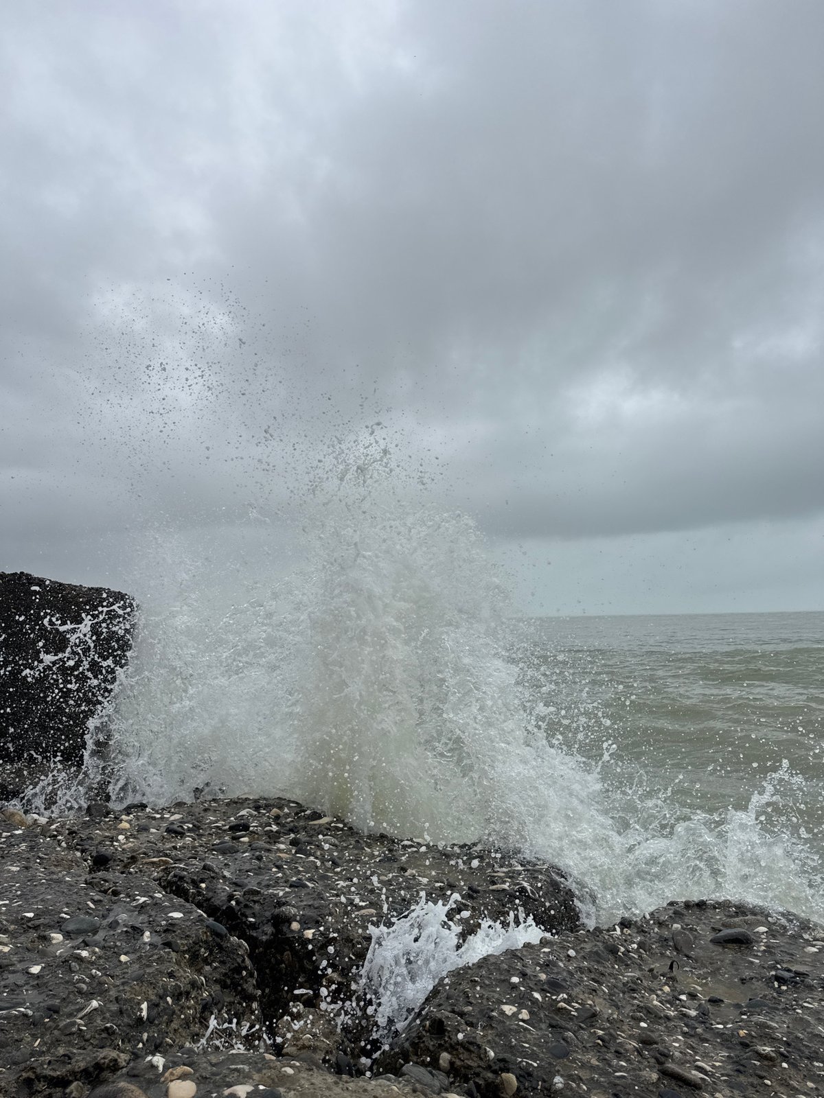 Two people observe waves at Sokhumi shoreline on cloudy day