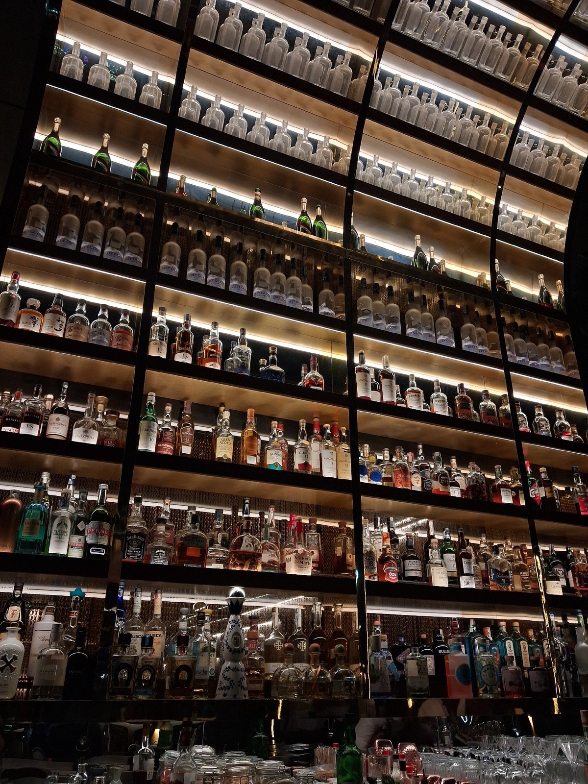 Bar establishment displays extensive liquor collection on illuminated shelves