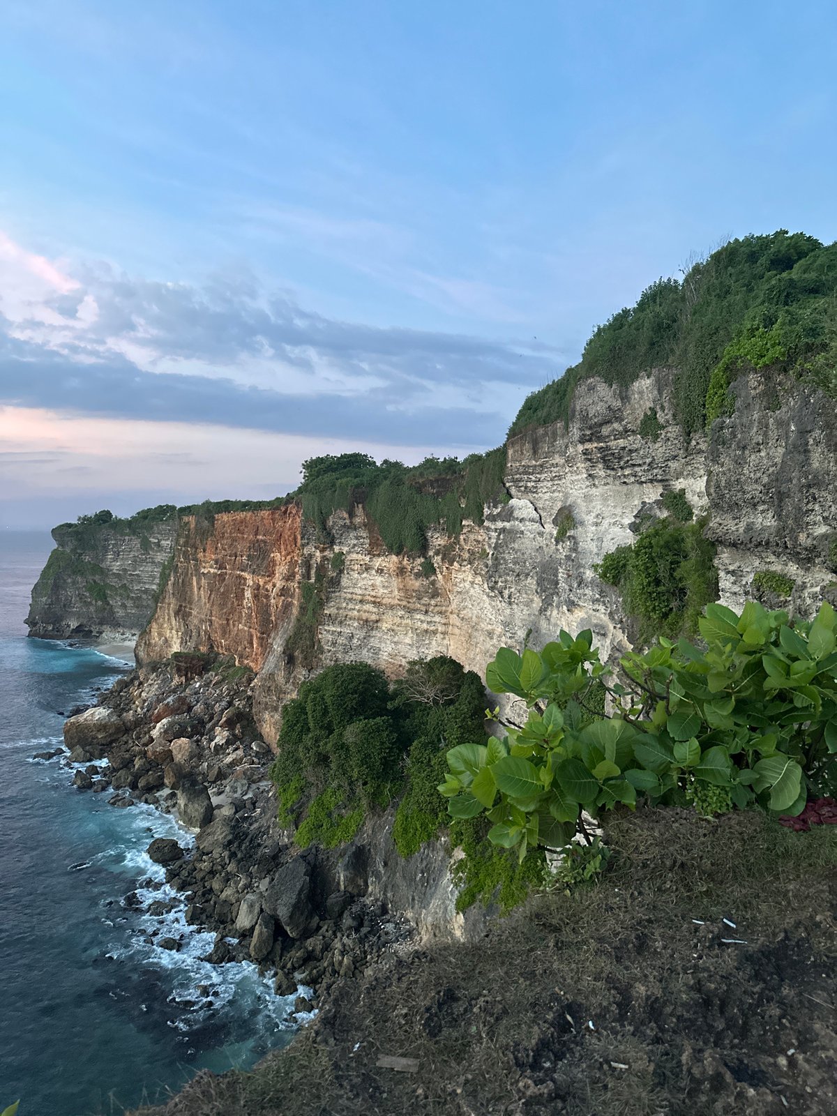 Tourists gather at Uluwatu cliffs during scenic sunset viewing
