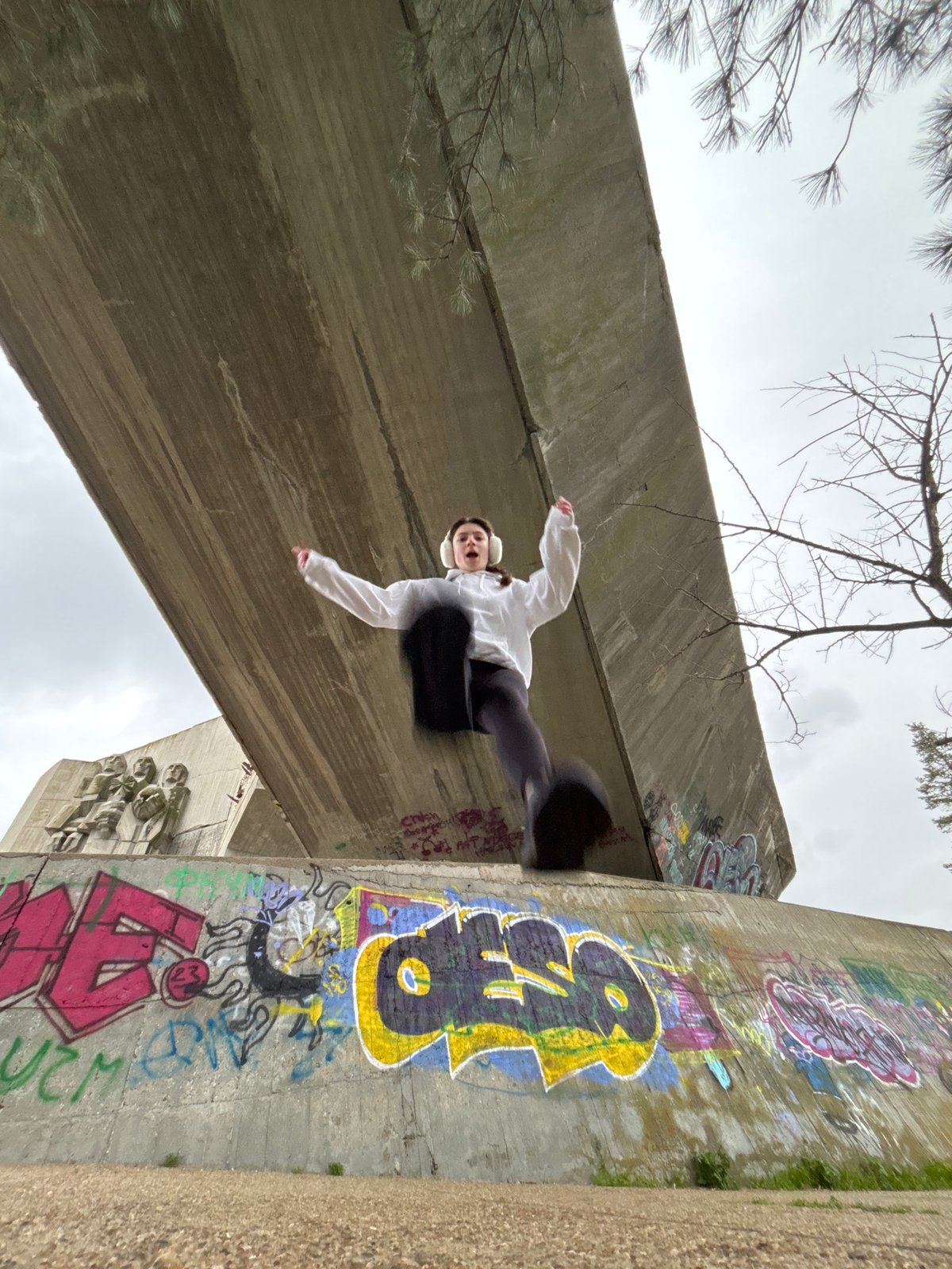 Person performs parkour moves near graffitied concrete structures