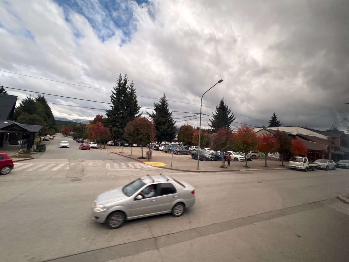 Vehicle crosses intersection in Villa La Angostura under overcast sky