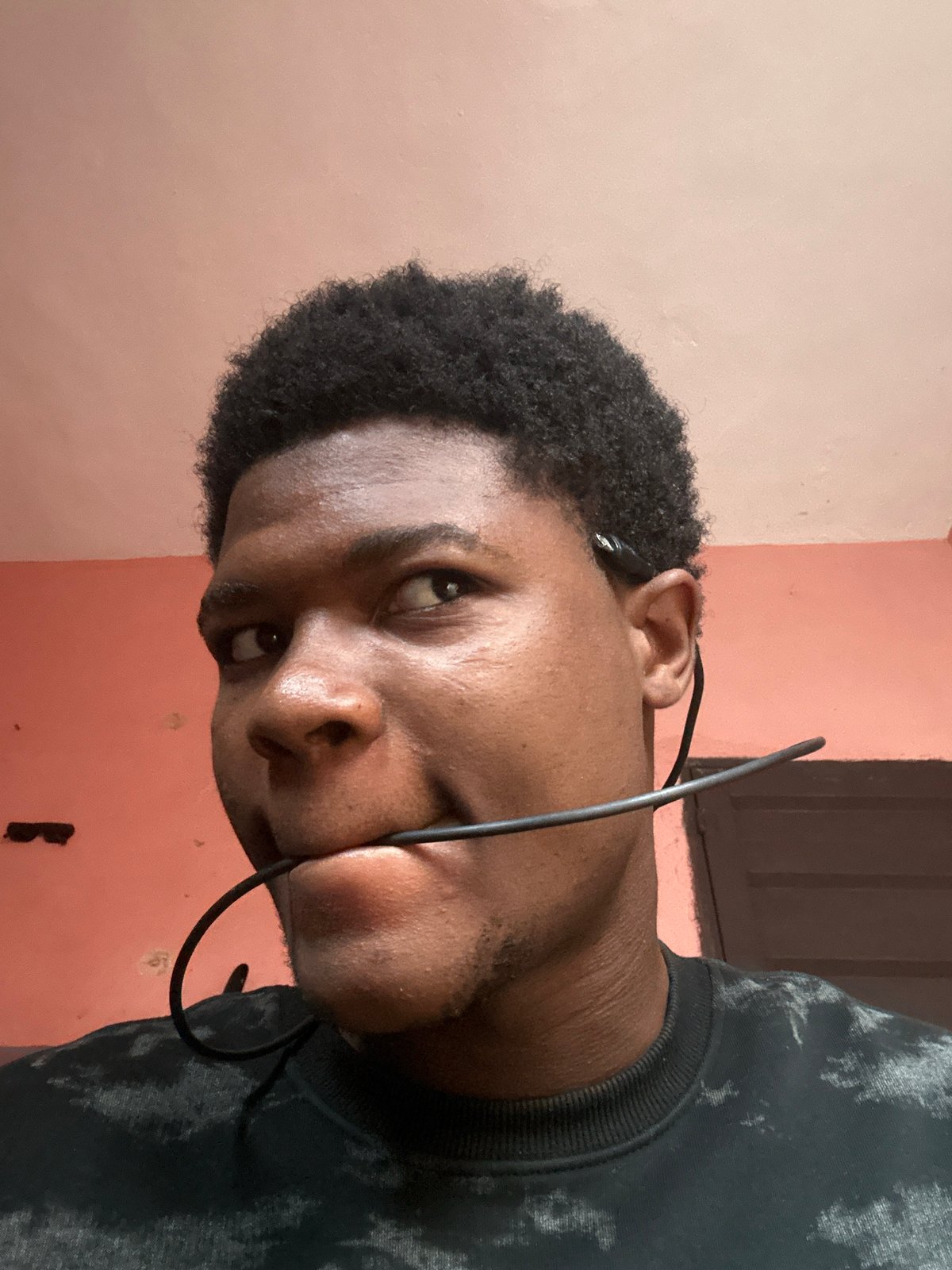 Lazy morning in an Ihiagwa bedroom, cables and earbuds in hand