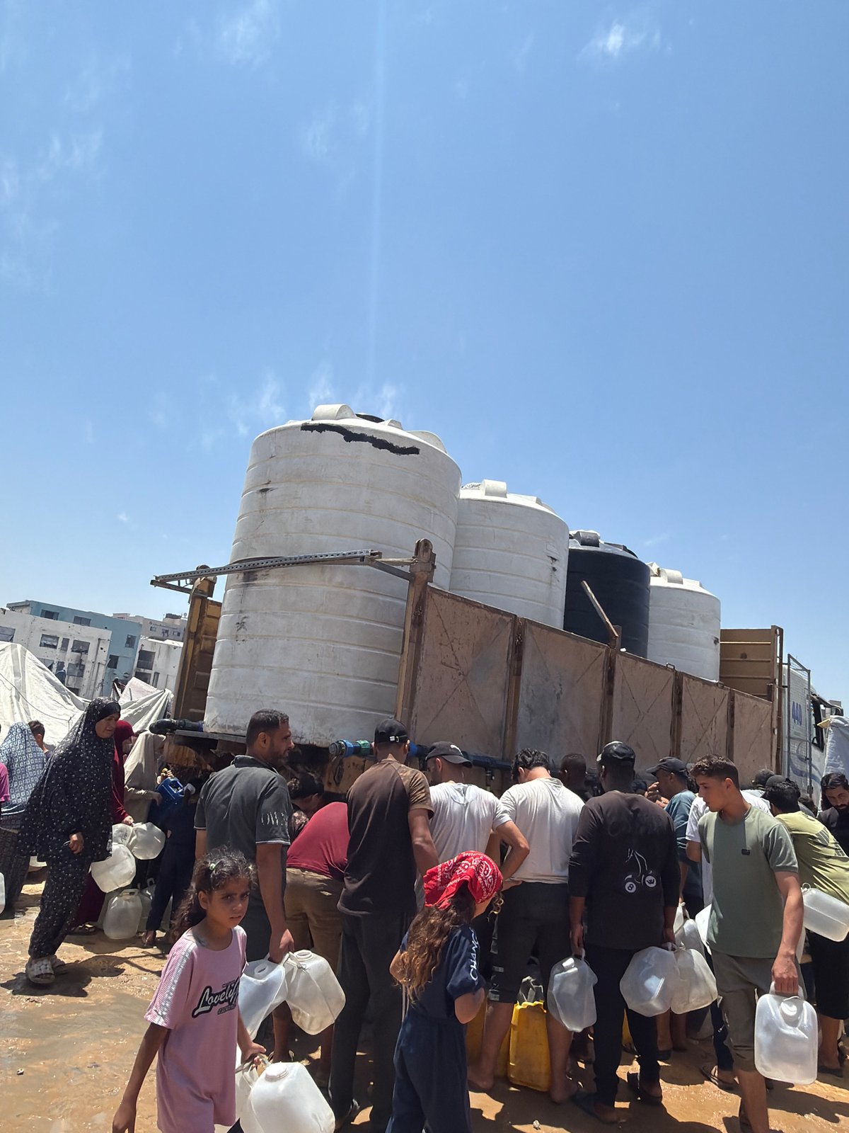 Gaza residents collect water from distribution truck amid displacement