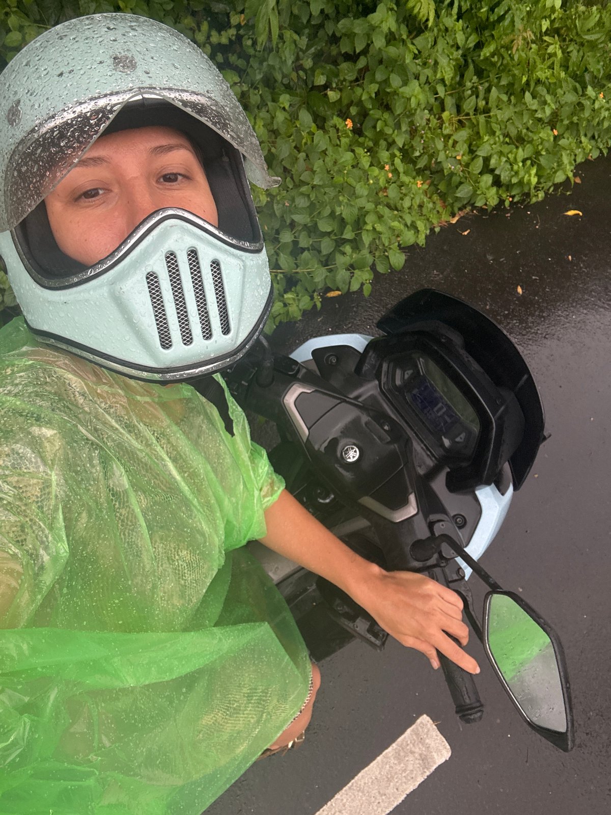 Motorcyclist in raincoat stops roadside in Kuta Selatan