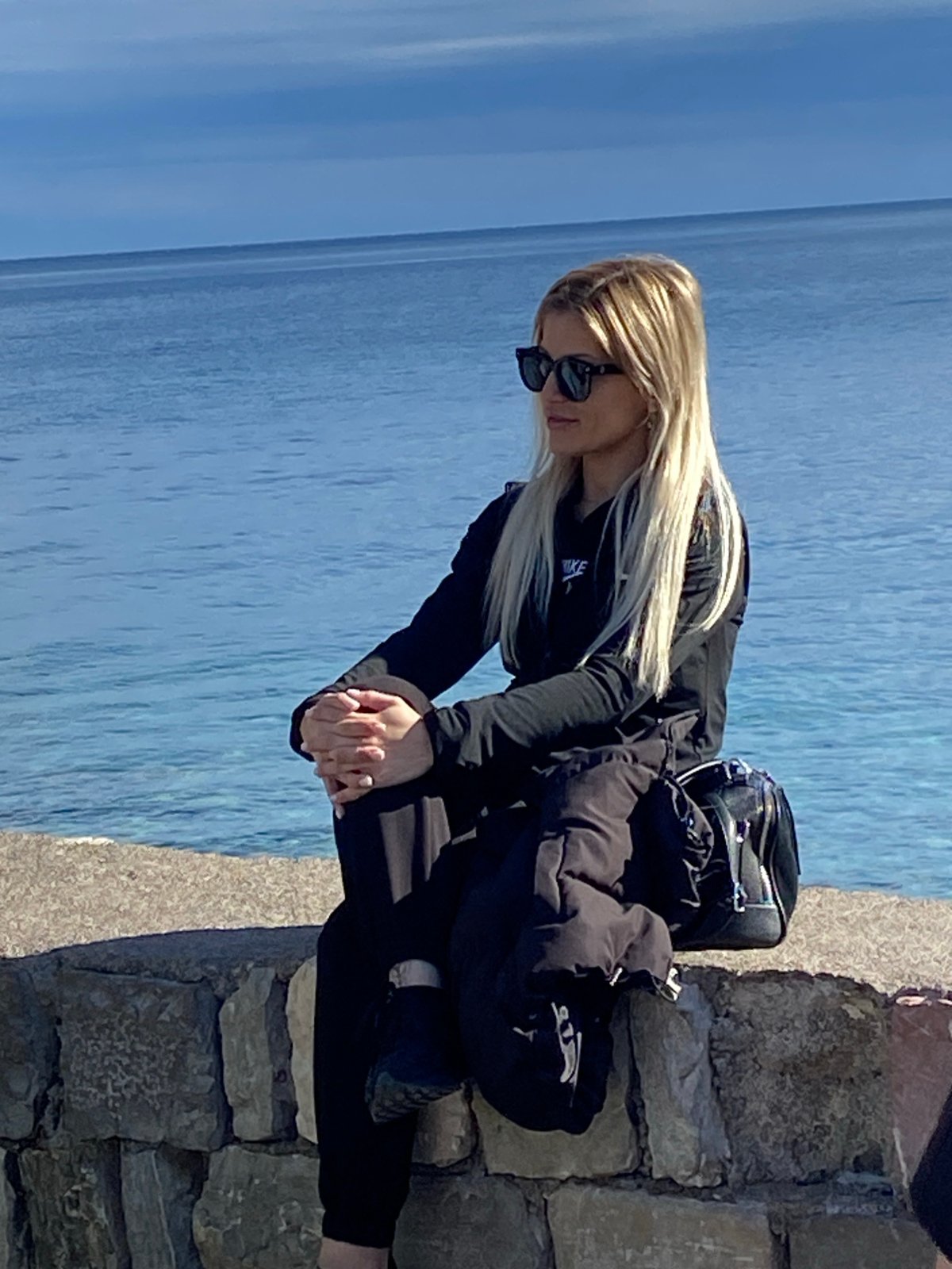 Woman photographed by seaside stone wall in Budva