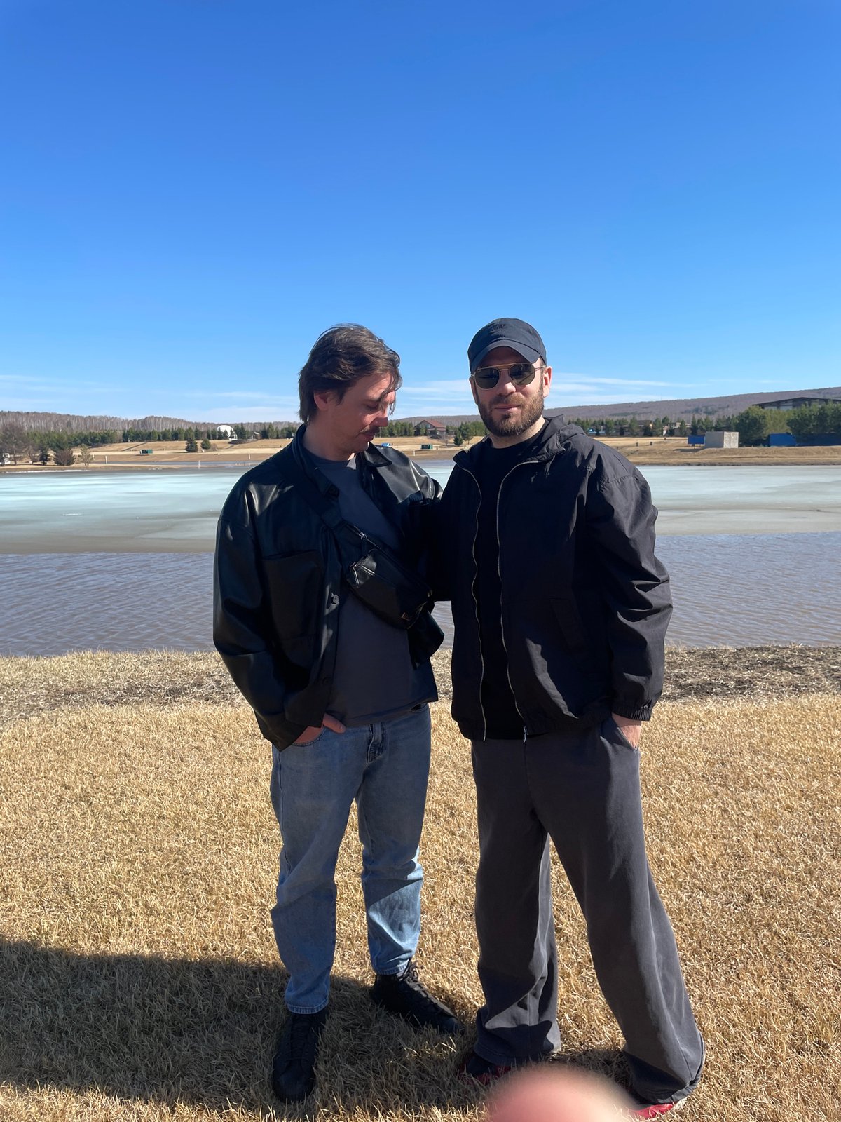Two men photographed by lake in sunny Emel'yanovo, Russia