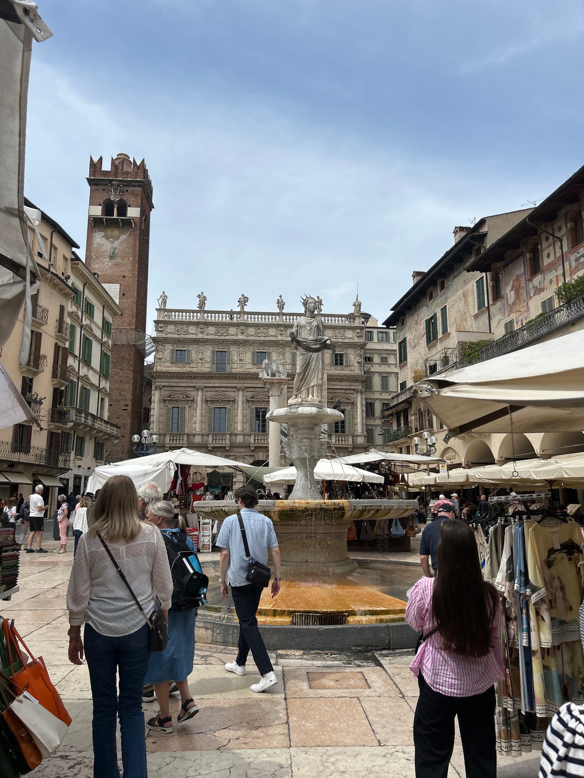 Pedestrians documented in historic Verona piazza during midday