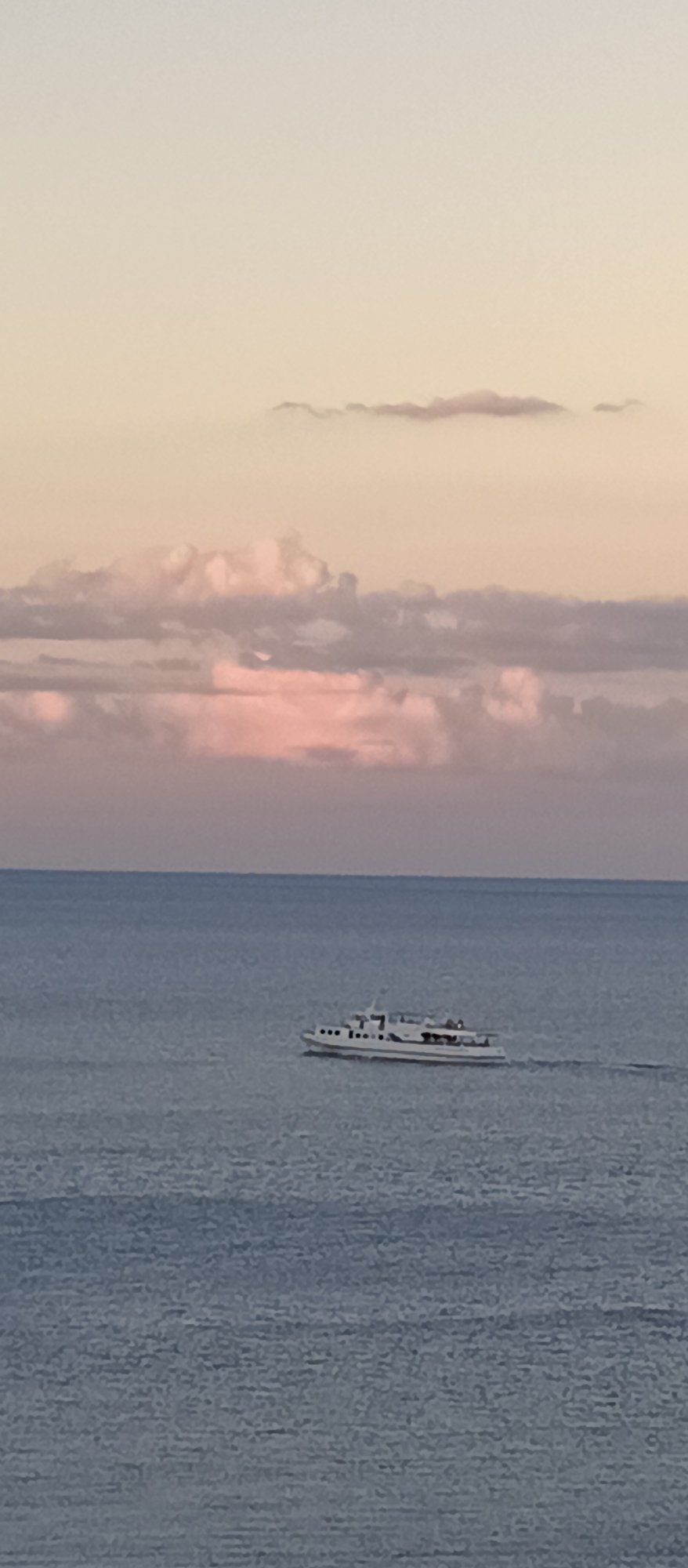 Dusk at a rocky coastal overlook, ferry on calm water