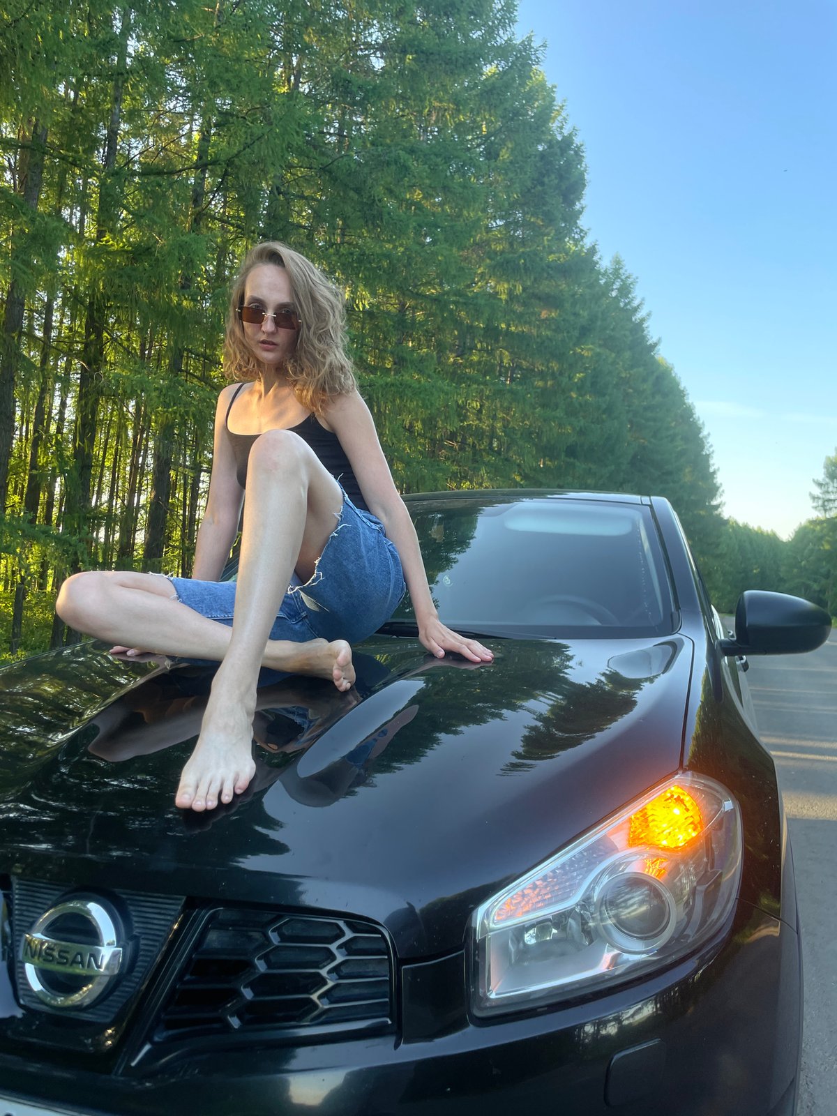 Woman sits on SUV hood near Russian forest road