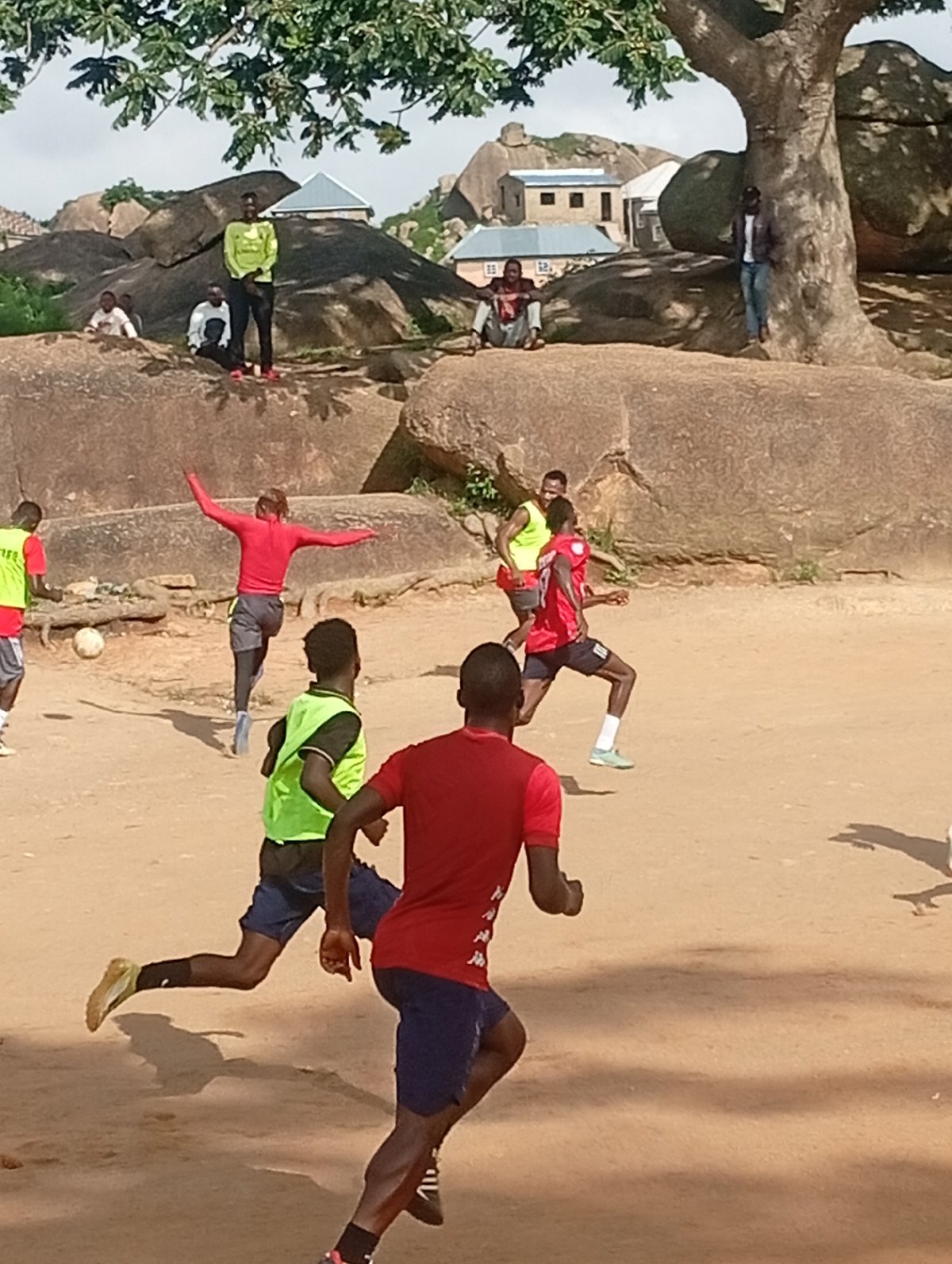 Pickup soccer on a dusty dirt field near dramatic rock formations