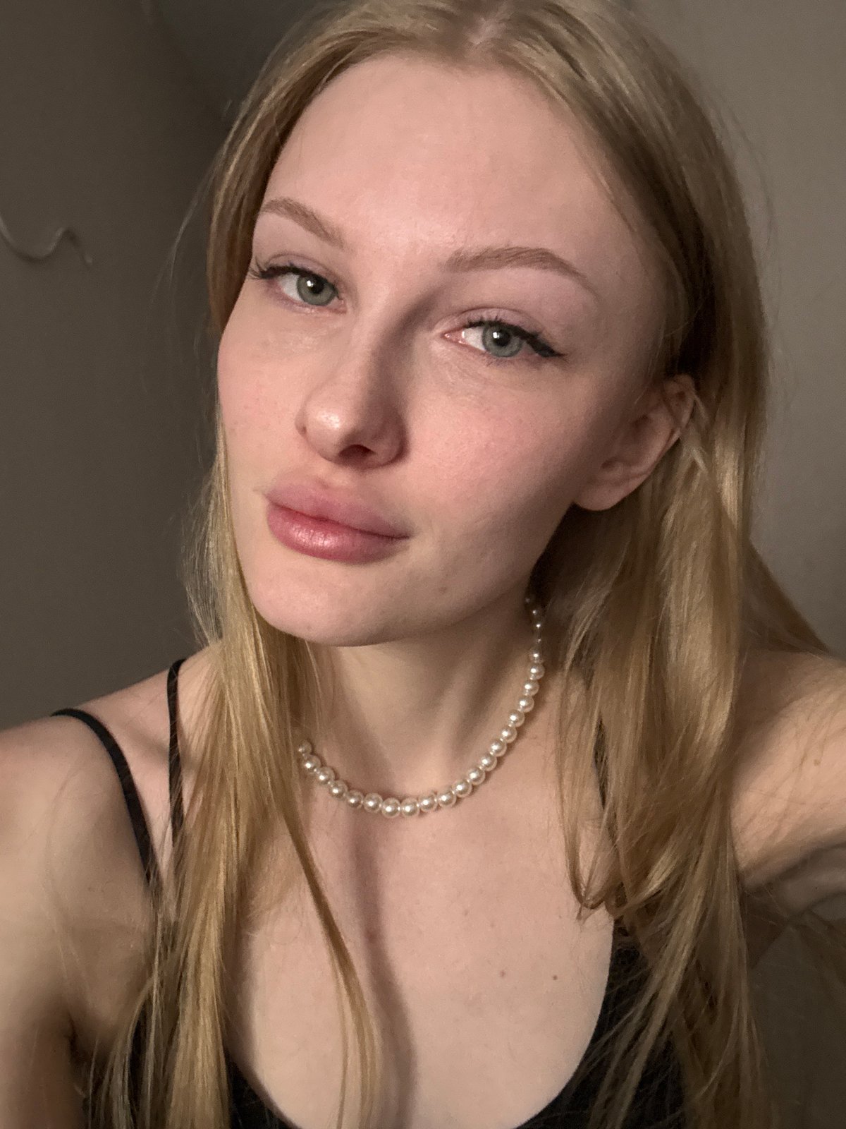 Woman takes selfies in black top, pearls in Perm