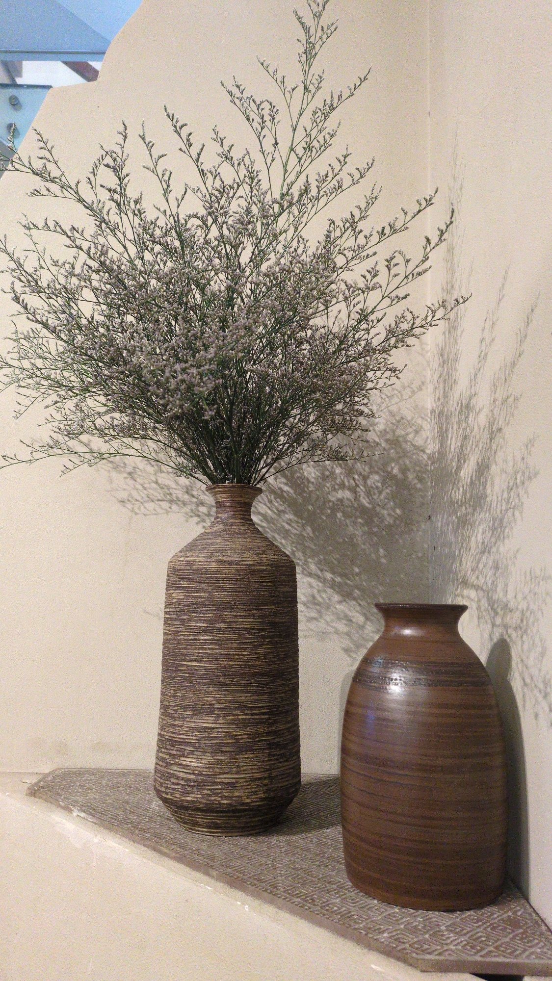Decorative vases with dried flowers displayed on shelf