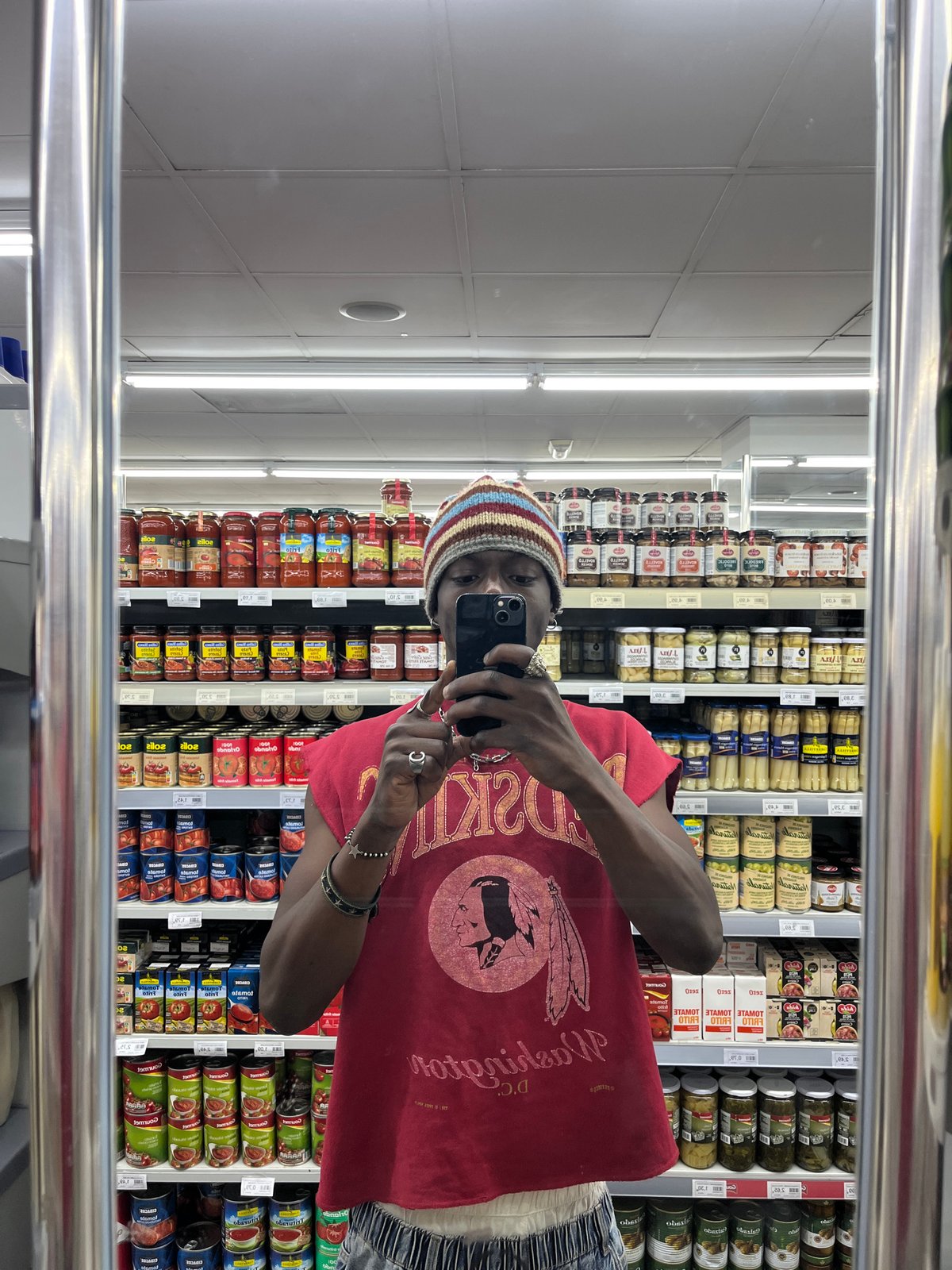 Person takes mirror selfies in Barcelona supermarket aisle