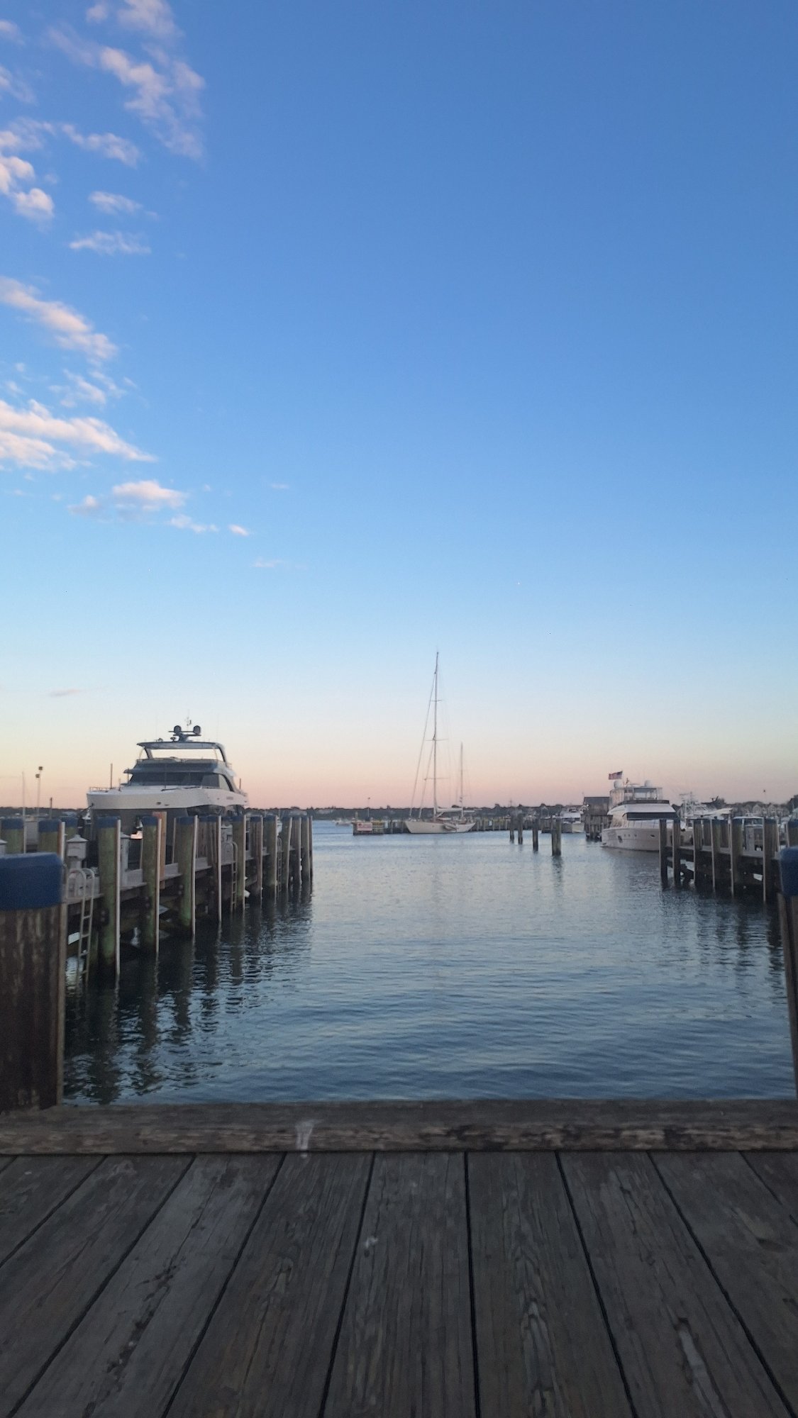 Nantucket harbor at golden hour, ferries and yachts docked at dusk