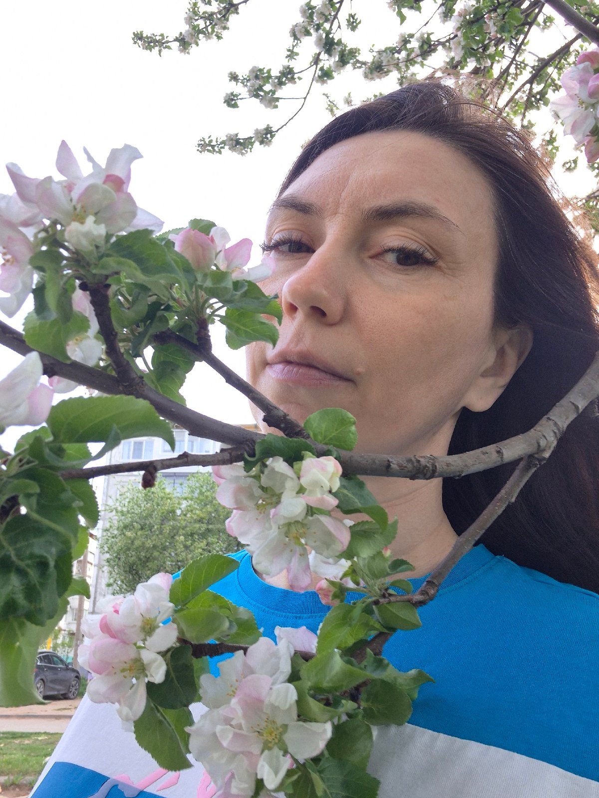 Woman poses with flowering tree blossoms in urban setting
