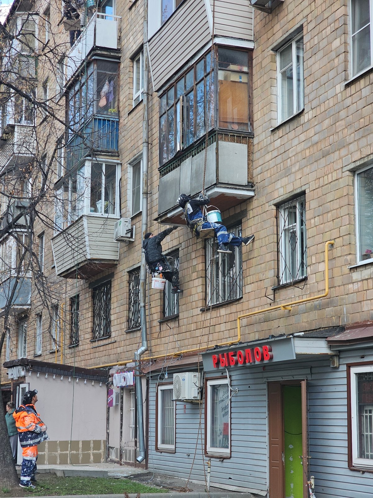 Workers paint building facade in Khimki, Russia