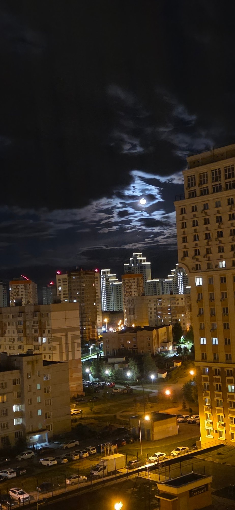Nighttime cityscape observed from elevated position, illuminated buildings visible