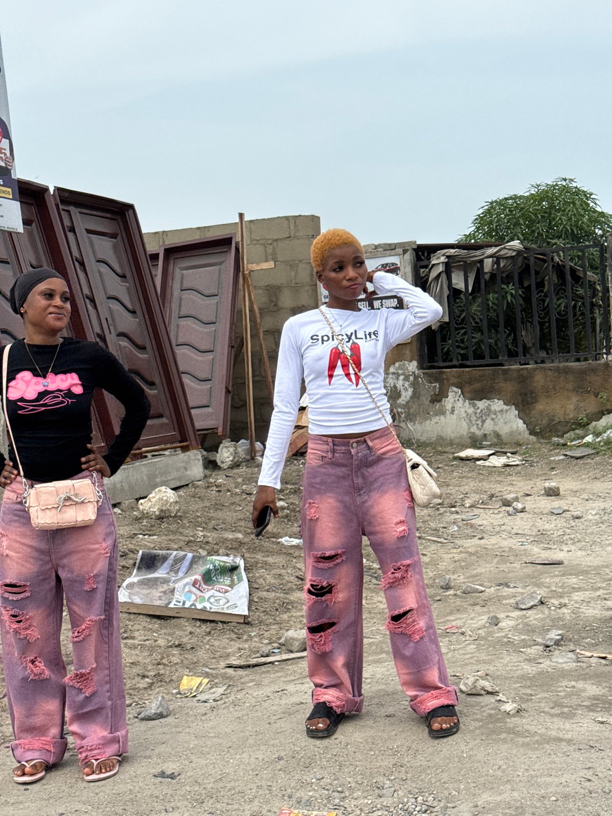 Two women stand on cracked pavement in Ado, Nigeria