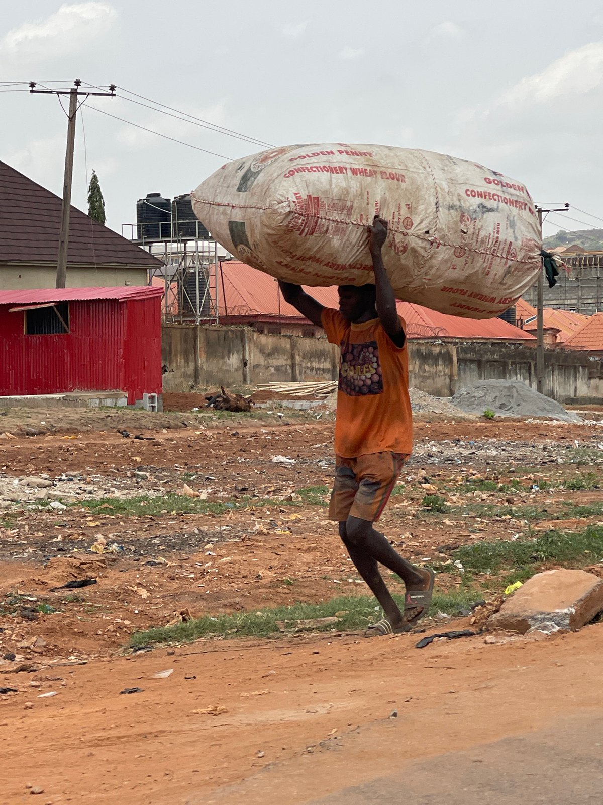 Manual laborer pushes cart along Abuja roadside