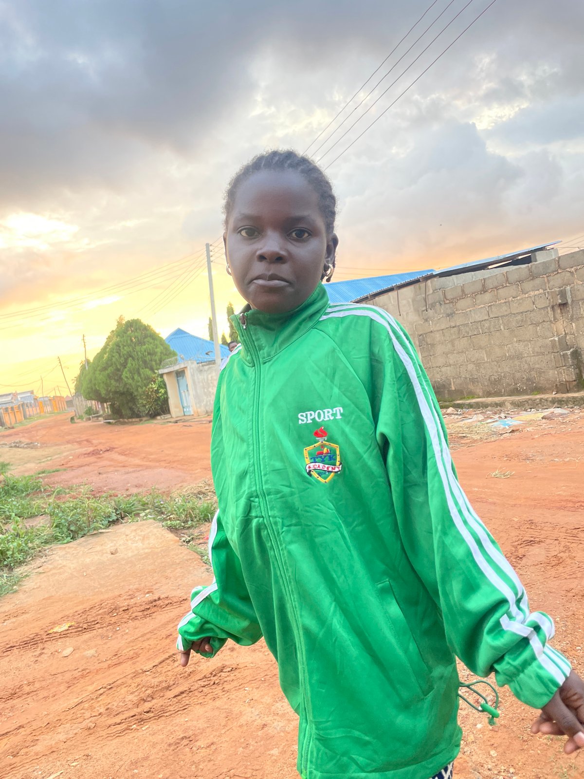 Green jacket, dirt road, Rido — a quiet Nigerian street moment.