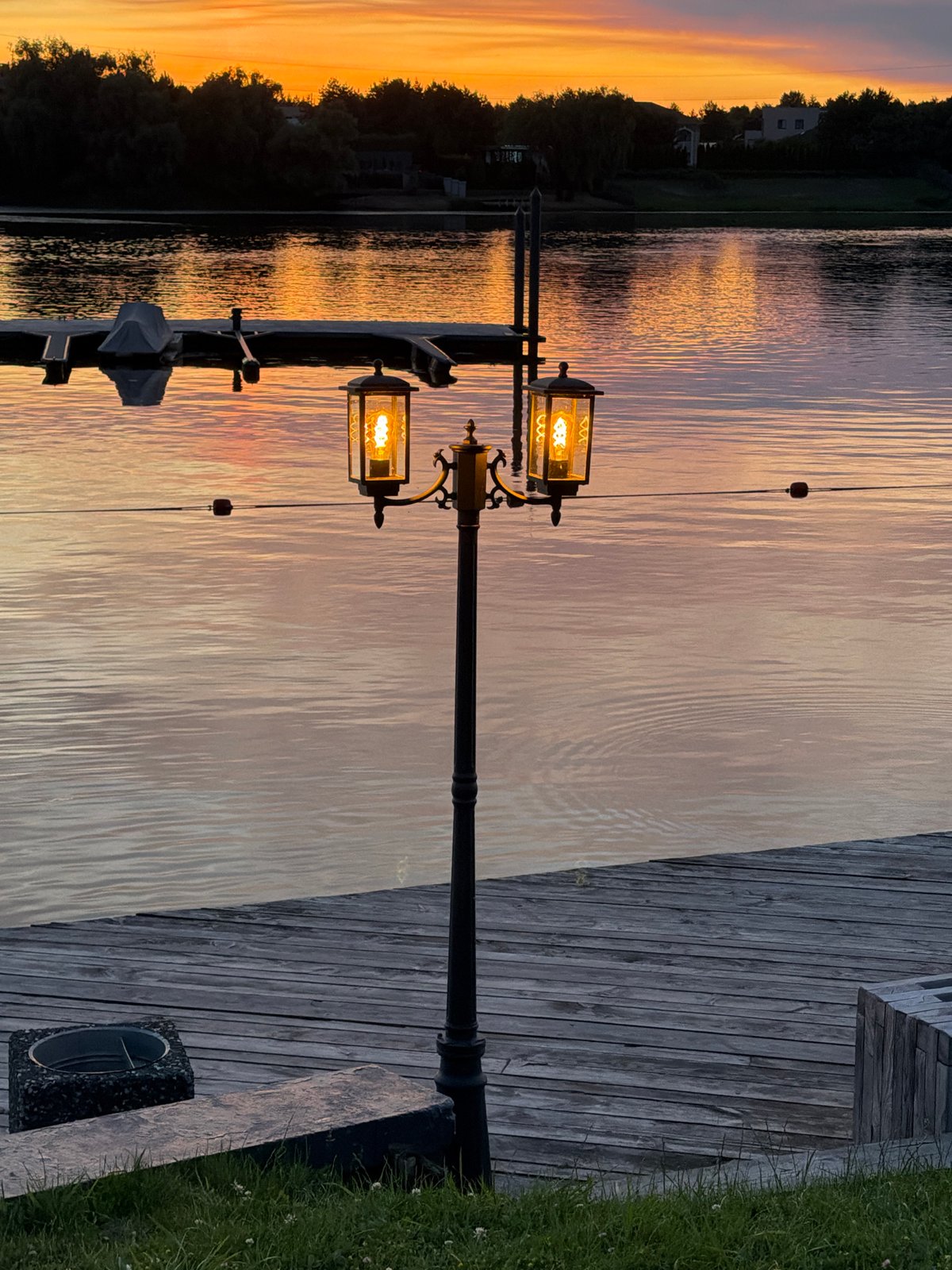 Waterfront sunset with warm lights and silhouetted trees