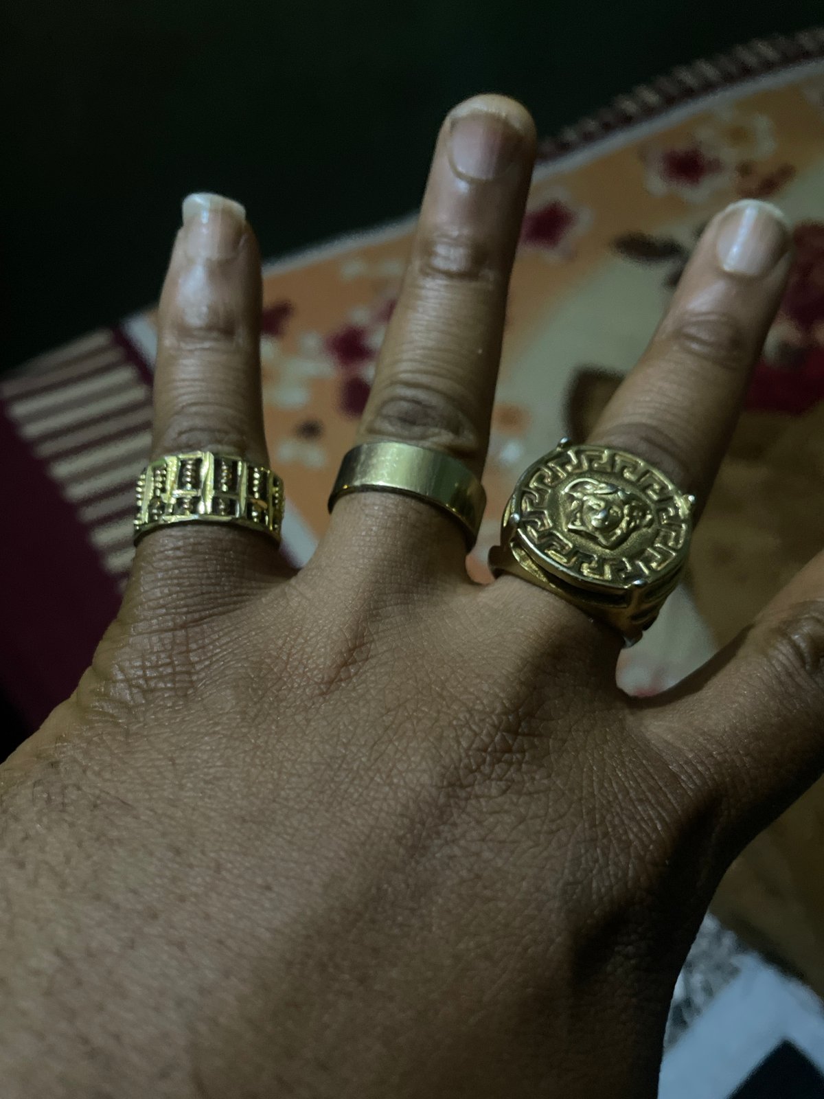 Gold rings on a hand against patterned textile, Jos Nigeria