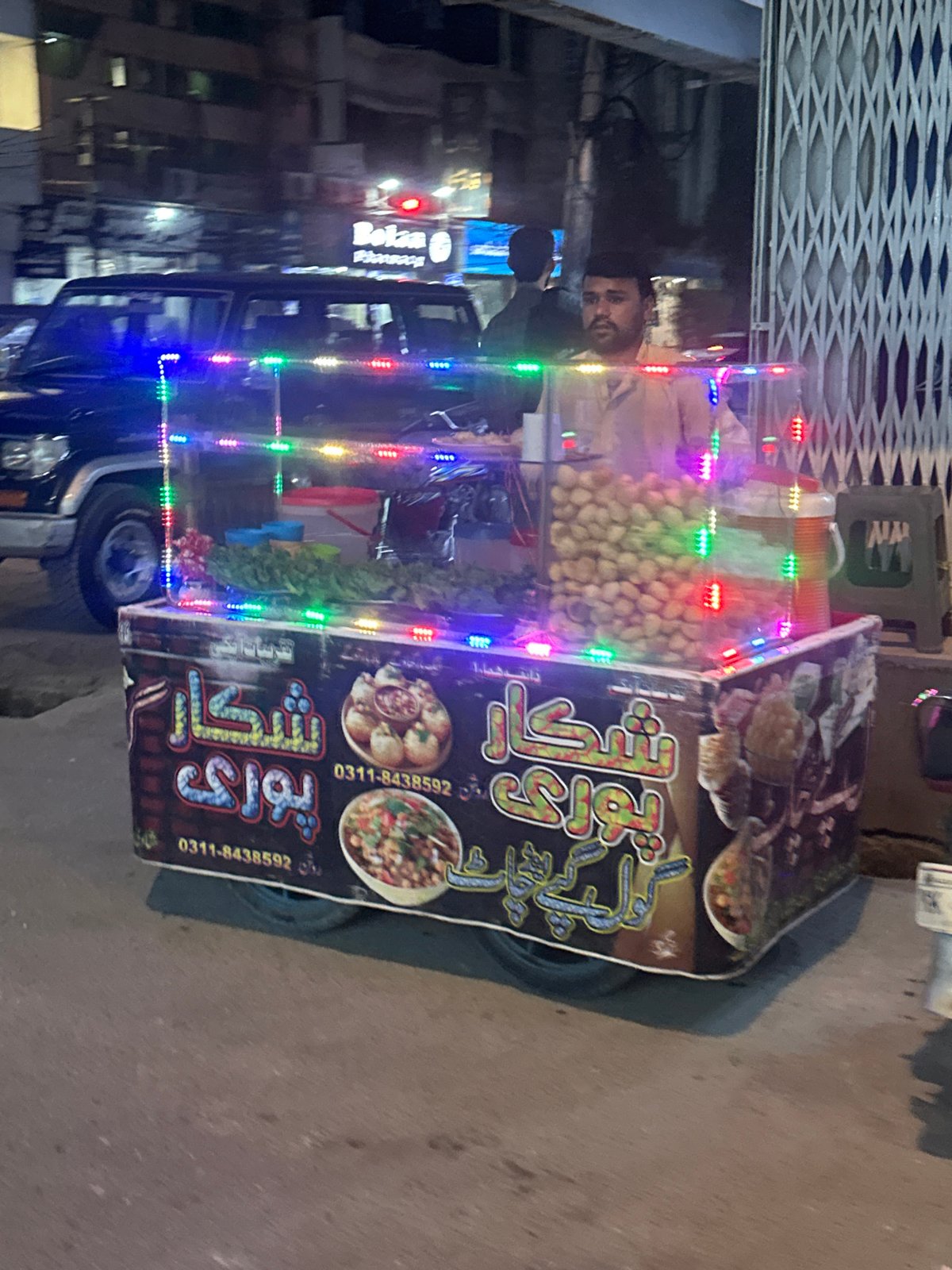 Street food vendor serves evening customers in South Asian neighborhood