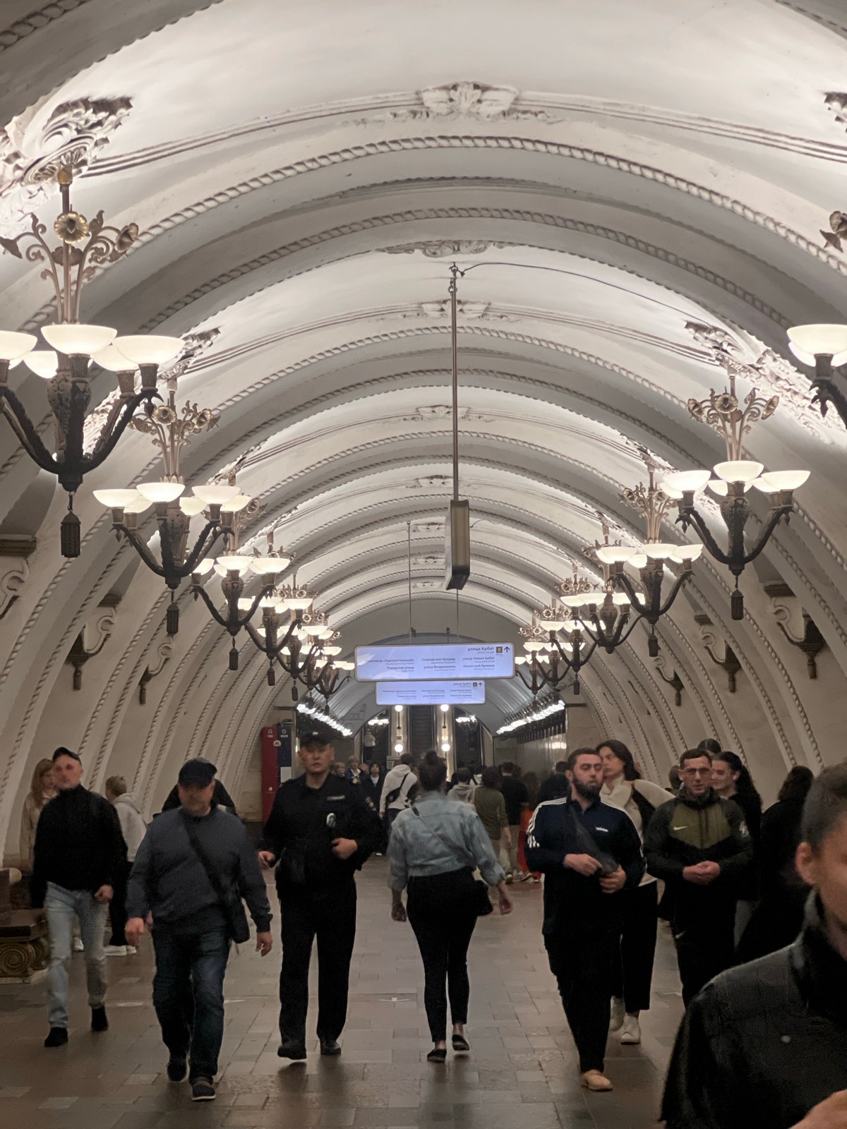 Pedestrians traverse ornate subway station with decorated arched ceilings