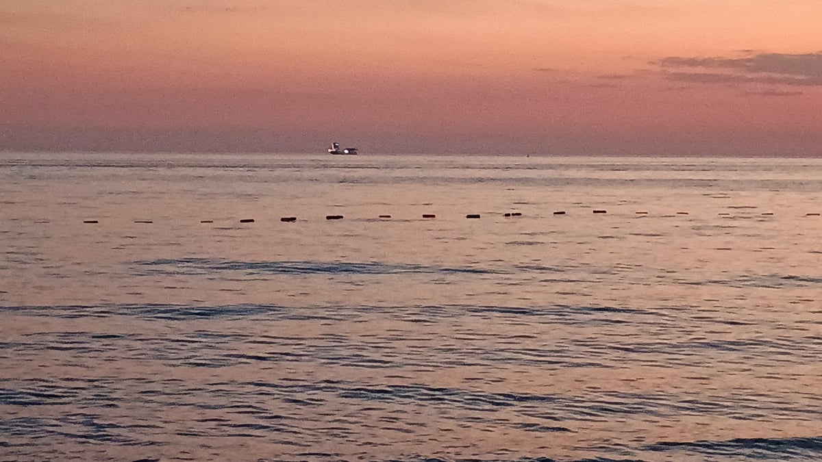 Coastal sunset gathering draws beachgoers, diners, anglers to waterfront