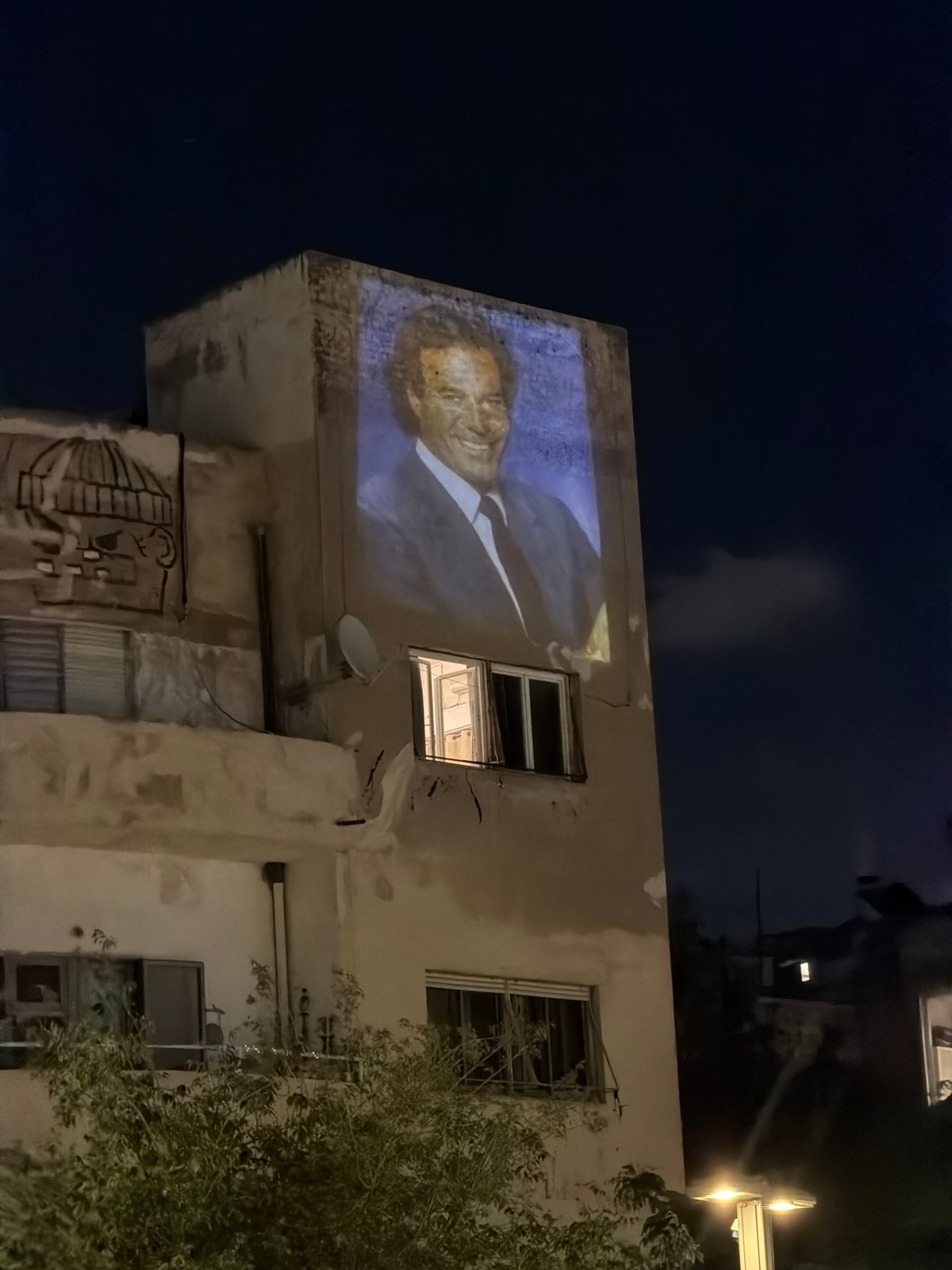 Large portrait projected onto Tel Aviv building at night