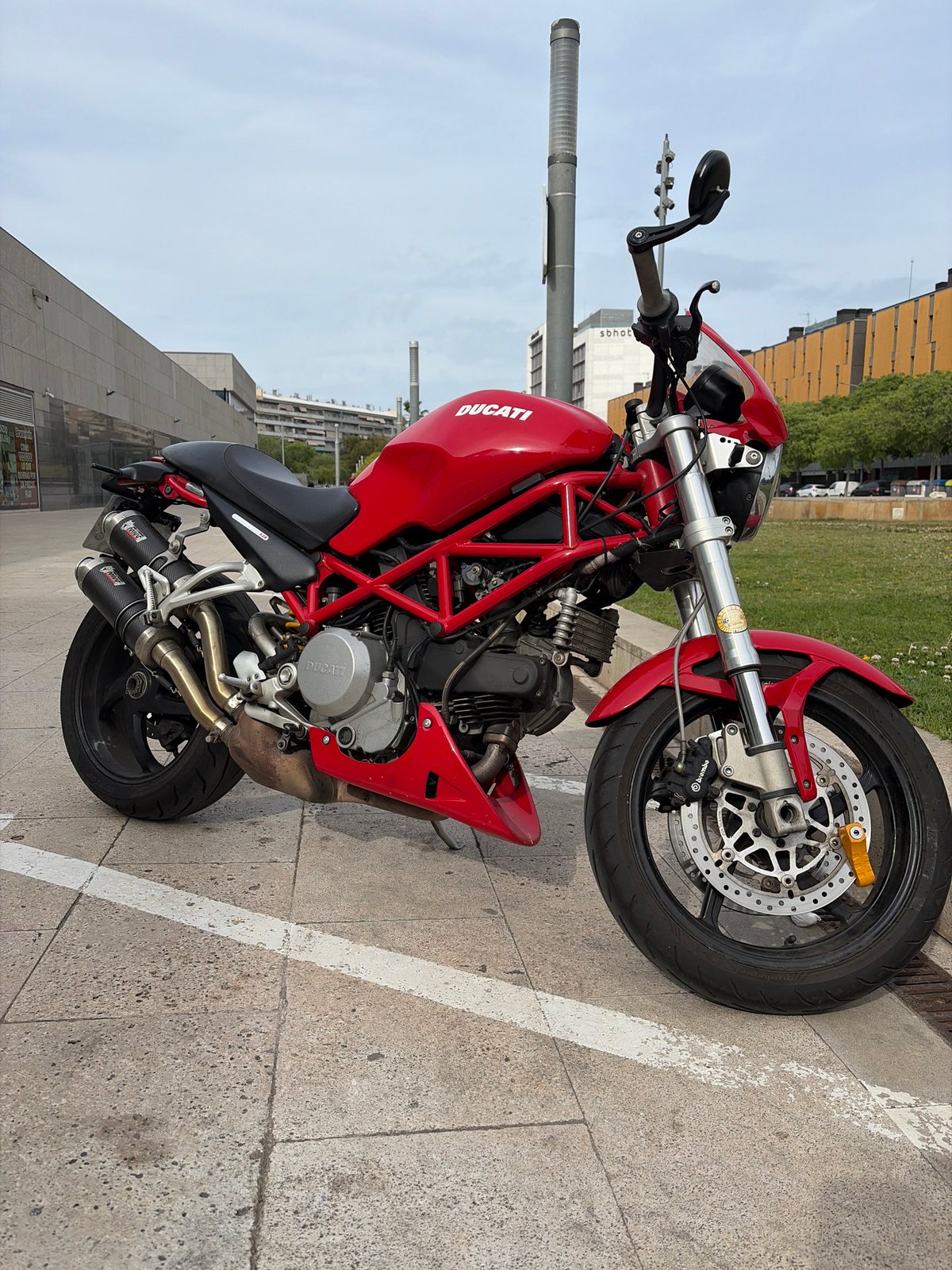 Red Ducati motorcycle parked on sidewalk in Spanish city