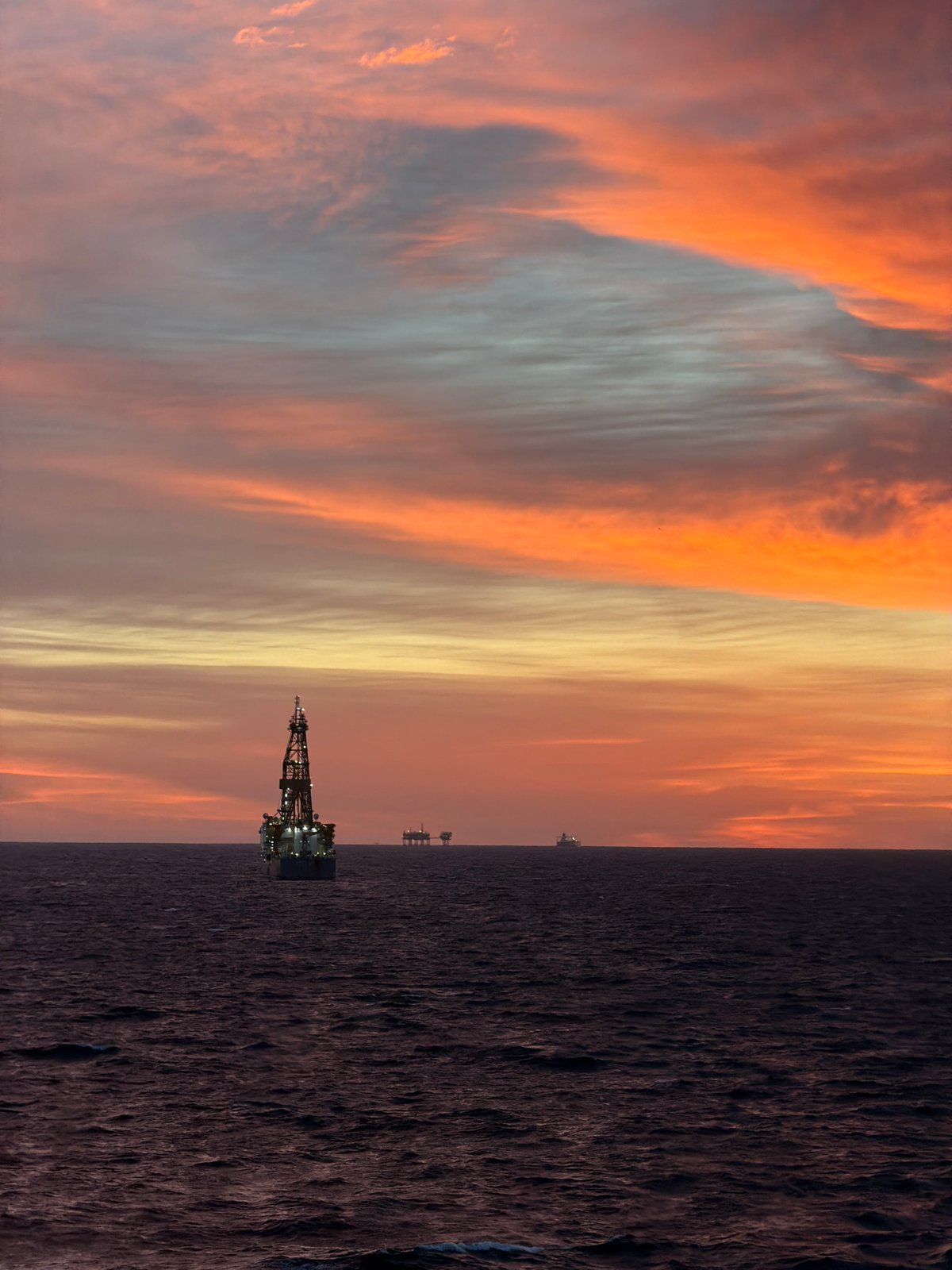 Offshore oil rig observed during dramatic sunrise over ocean