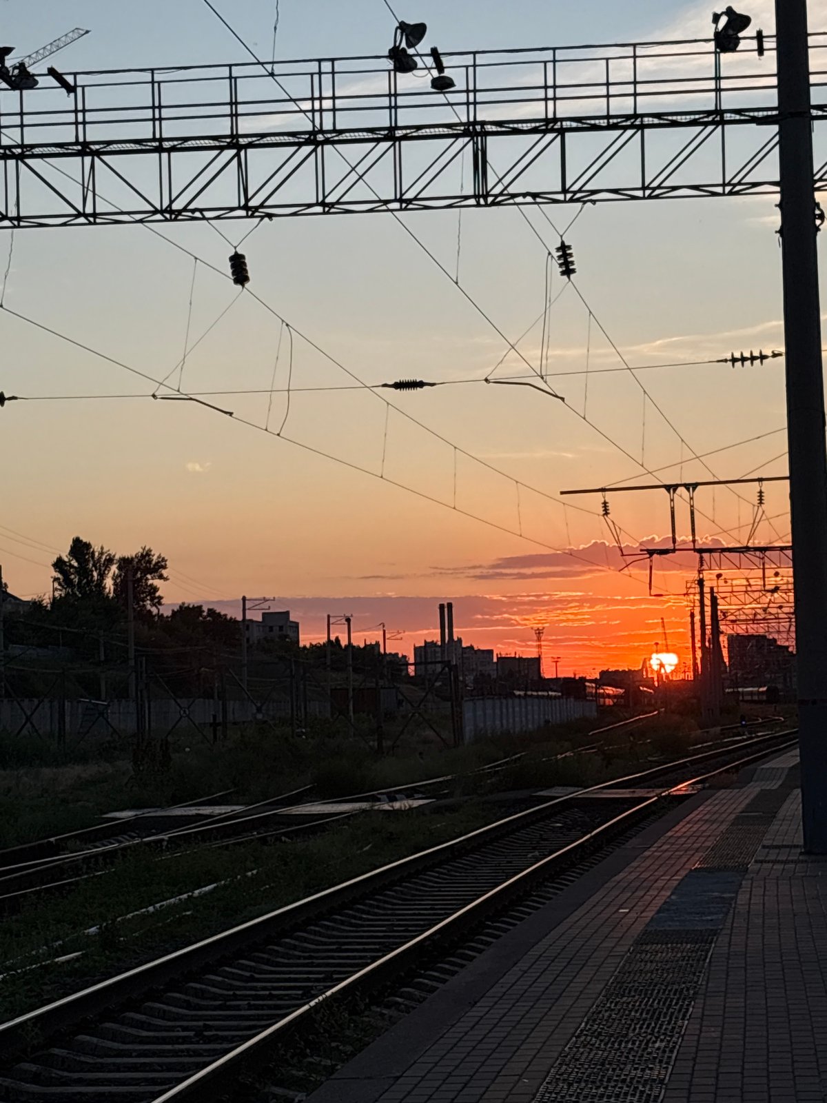 Sunset scenes documented at Volgograd railway station with trains, flags