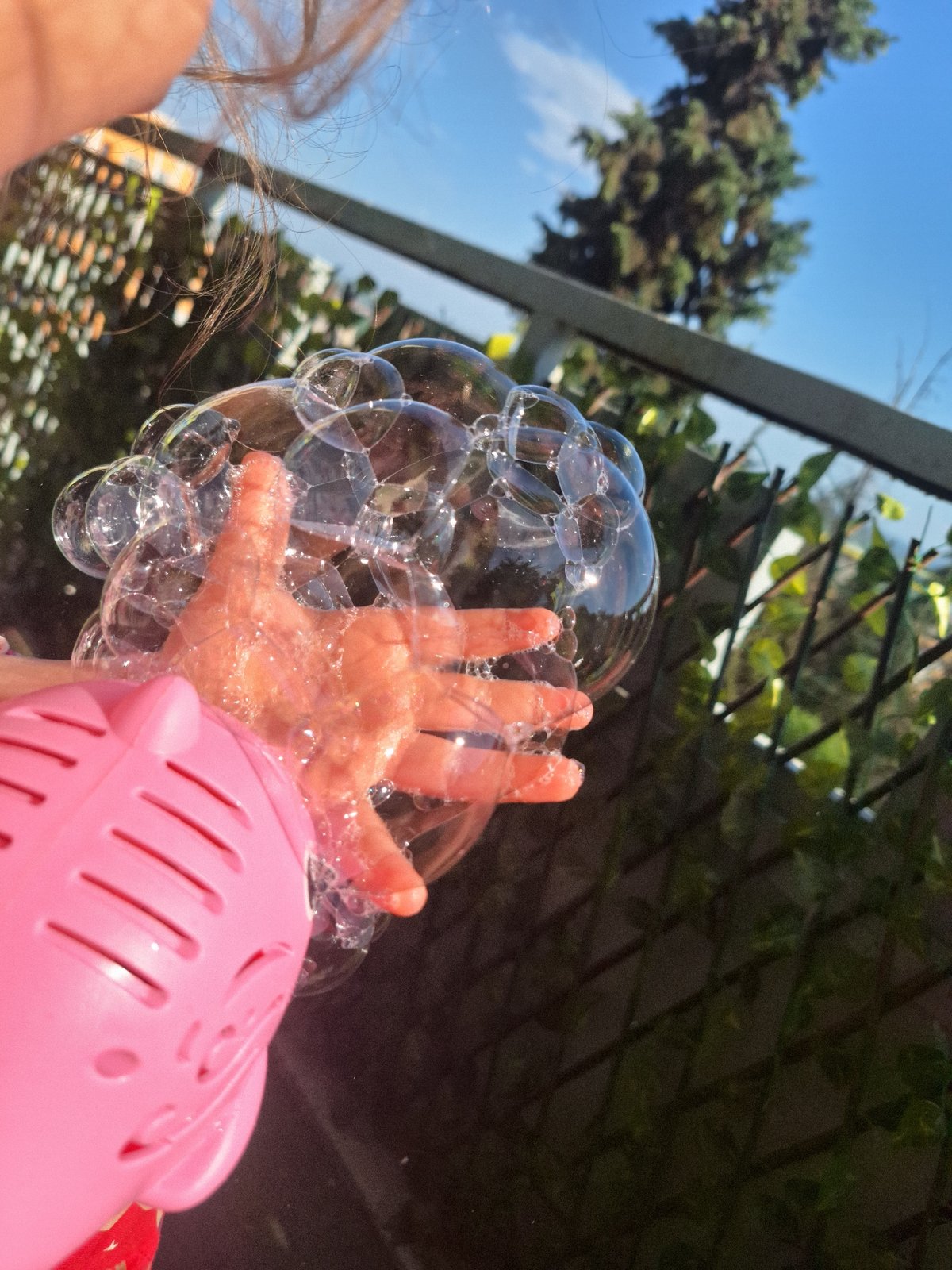 Child plays with pink pig bubble machine outdoors