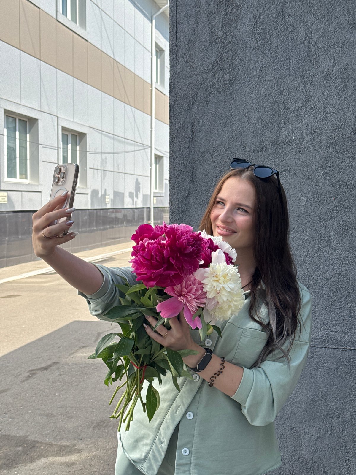 Woman photographs selfies with peony bouquets in Chaikovsky, Russia