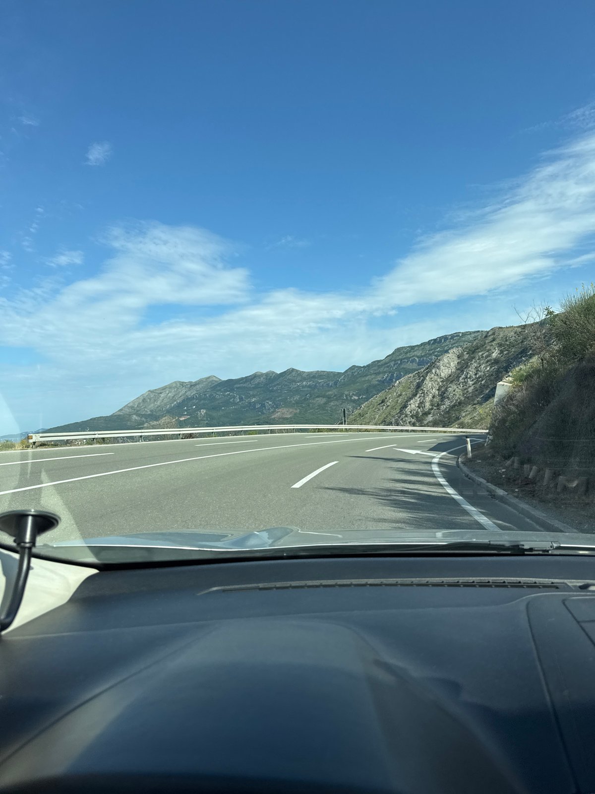 Vehicle travels Montenegro coastal roads past mountains and Adriatic Sea