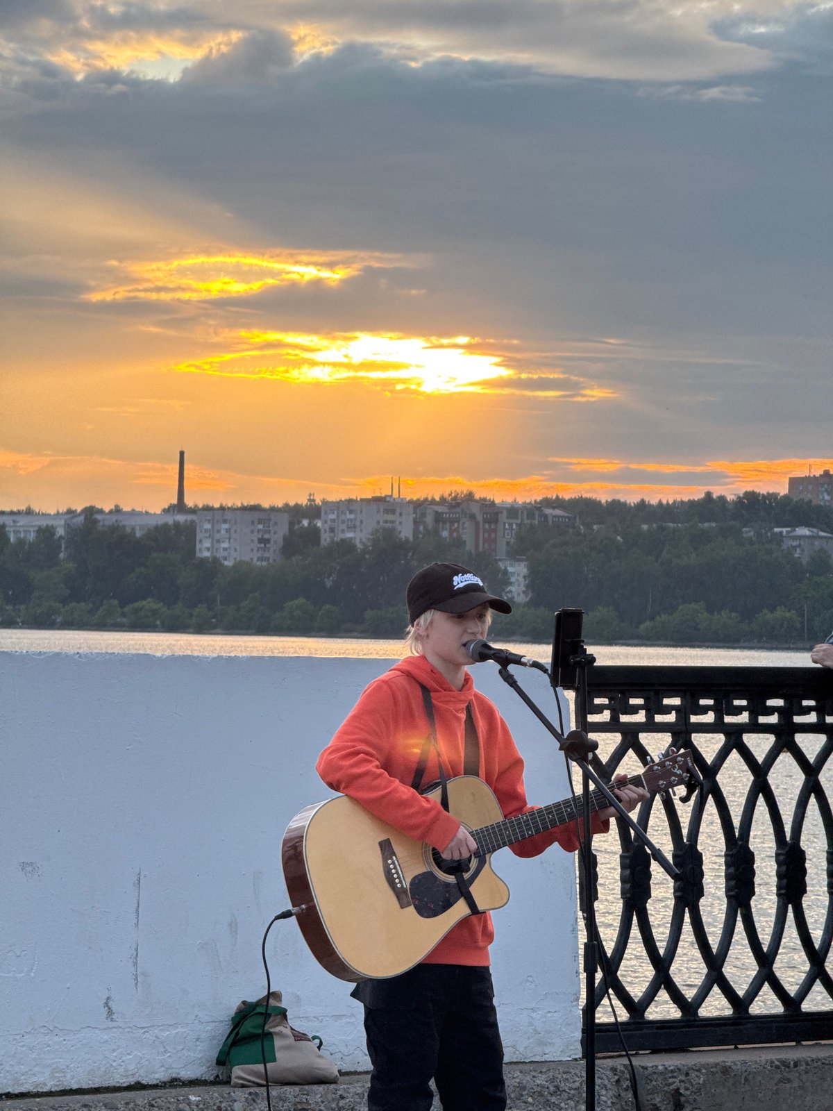 Street musician performs during sunset on Izhevsk riverfront embankment