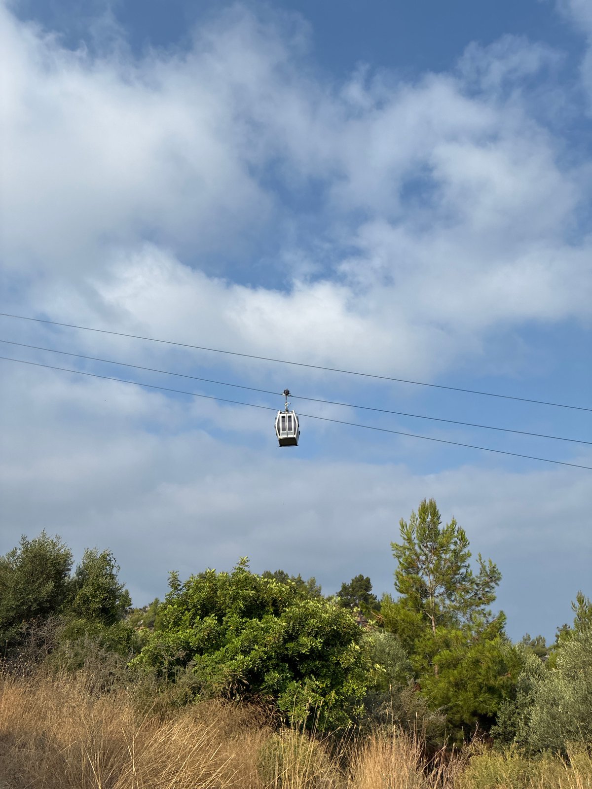 Cable cars glide above Alanya's coastal hillside on a summer morning.