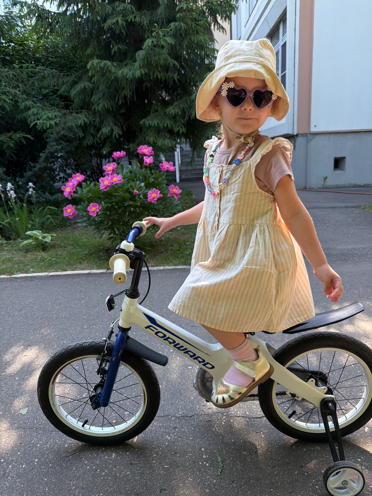 Child enjoys morning bike ride among blooming peonies in Moscow