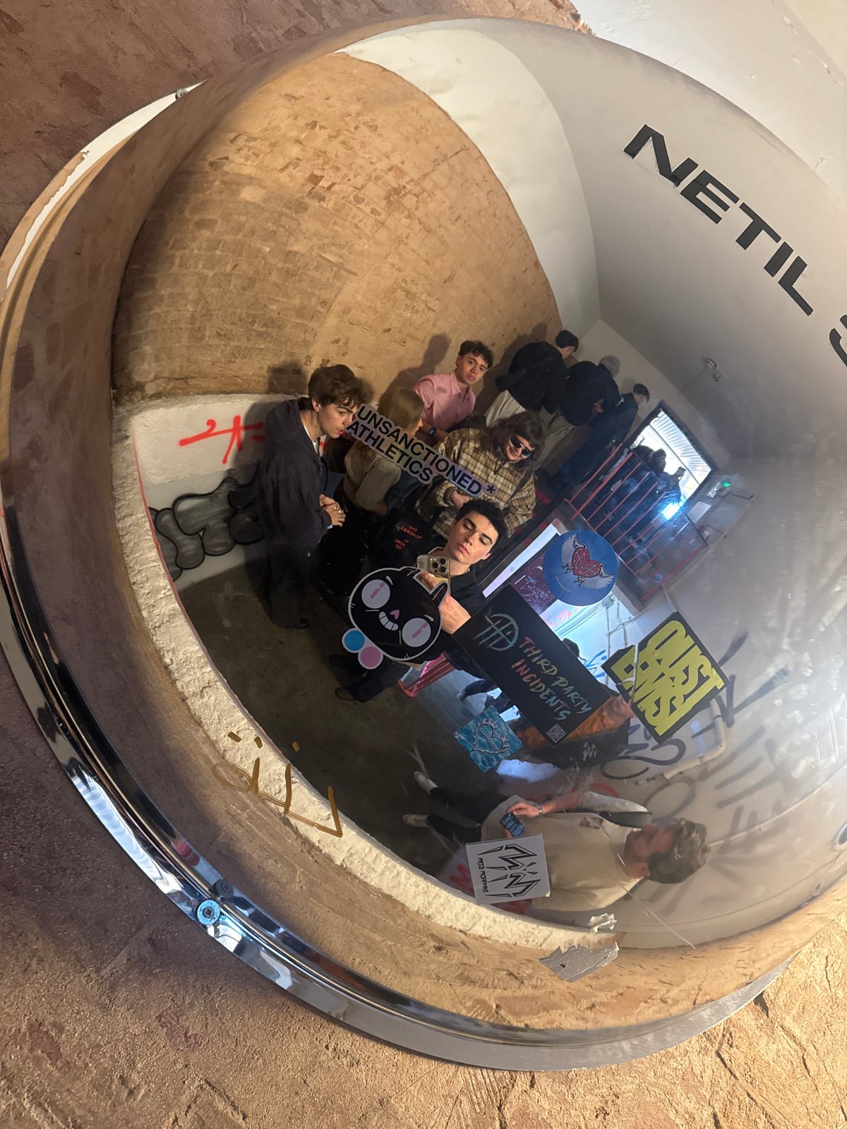 Young men gather at London exhibition space, captured in mirror