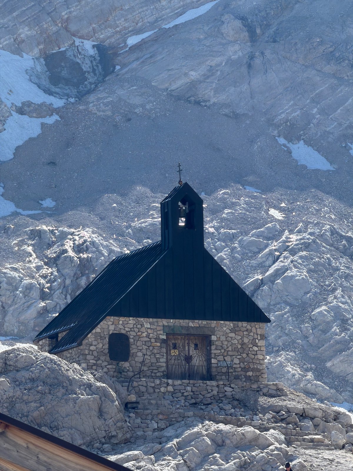Alpine chapel, aerial peaks, and parked snow groomers near Garmisch-Partenkirchen
