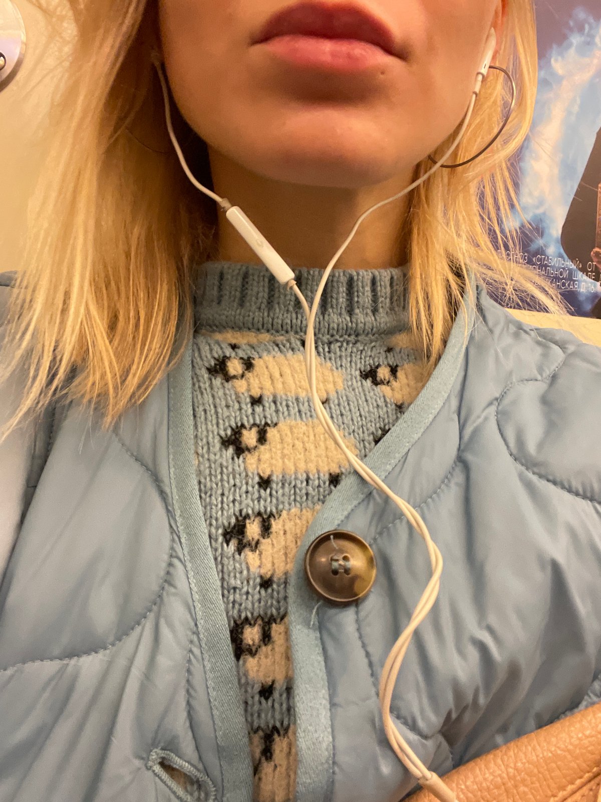 Person in earphones and quilted jacket captured indoors Moscow
