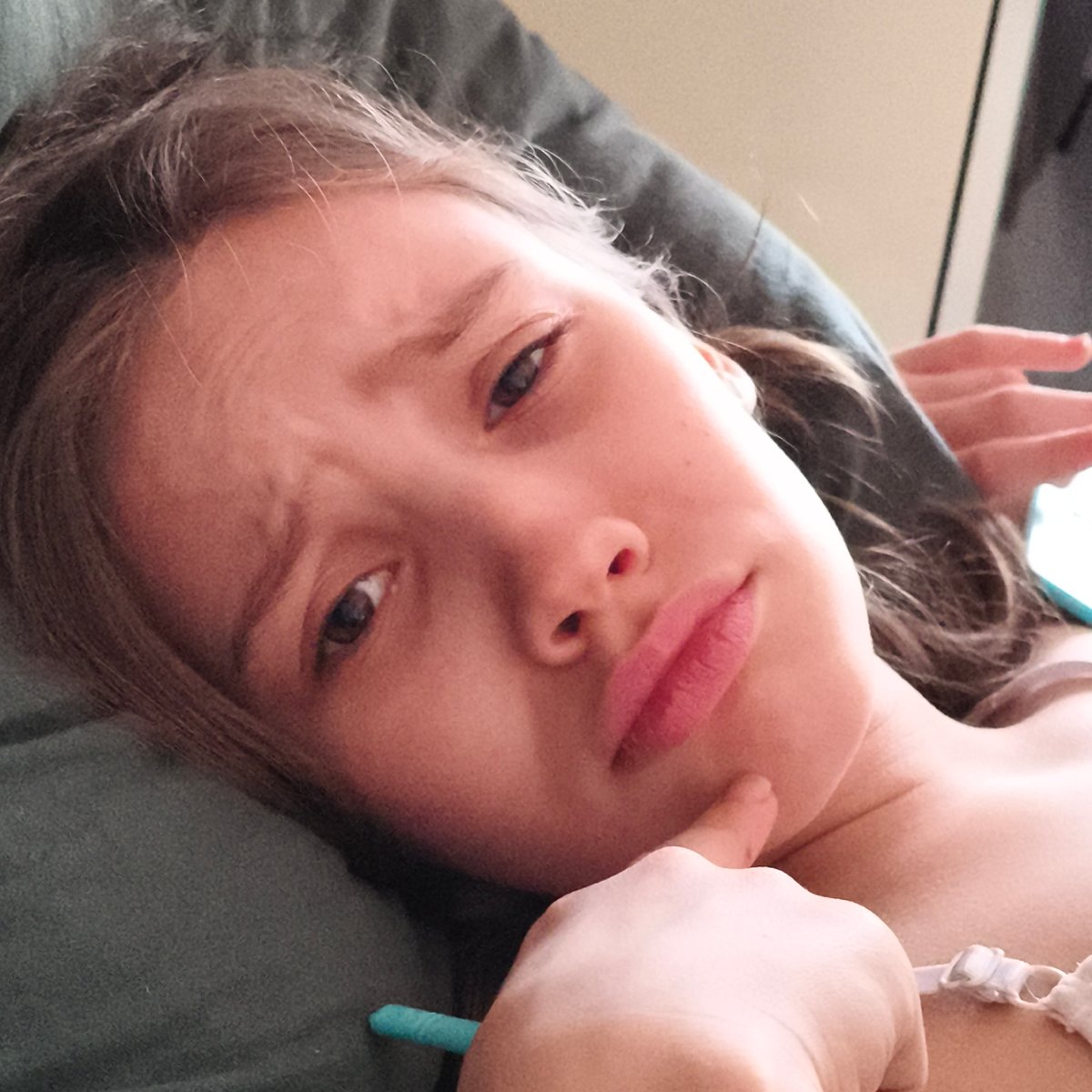 Young person poses thoughtfully on green couch