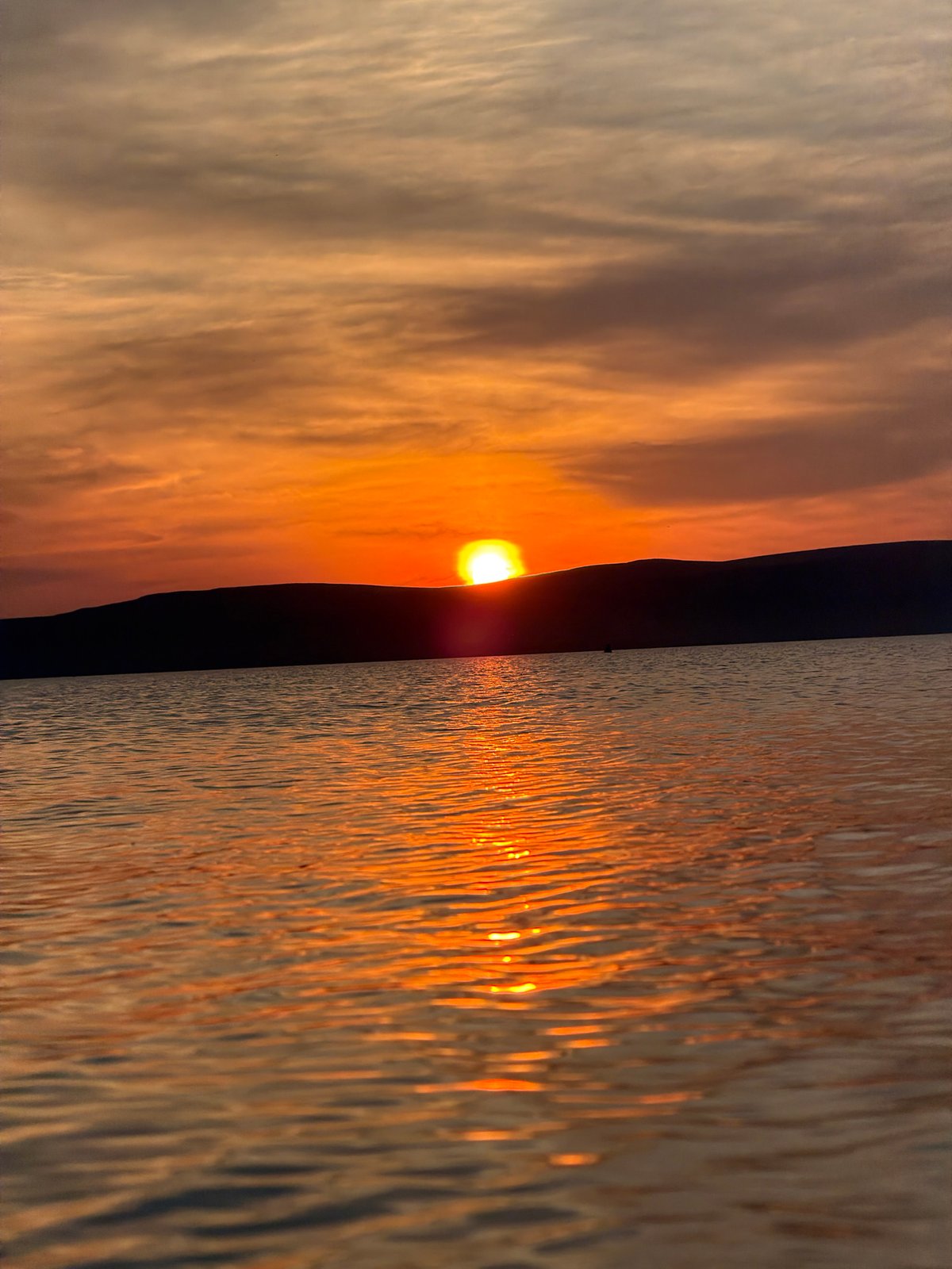 Sunset evening at a Siberian lake, mountains on the horizon
