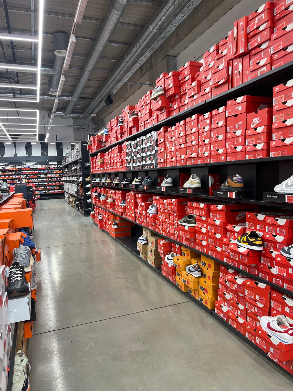 Nike store interior shows organized red shoebox display