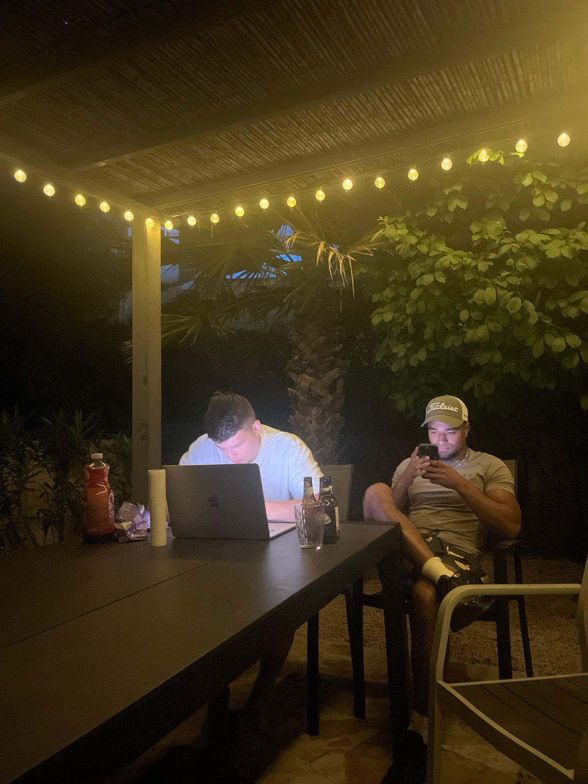 Three men gather at nighttime patio in Spanish coastal town